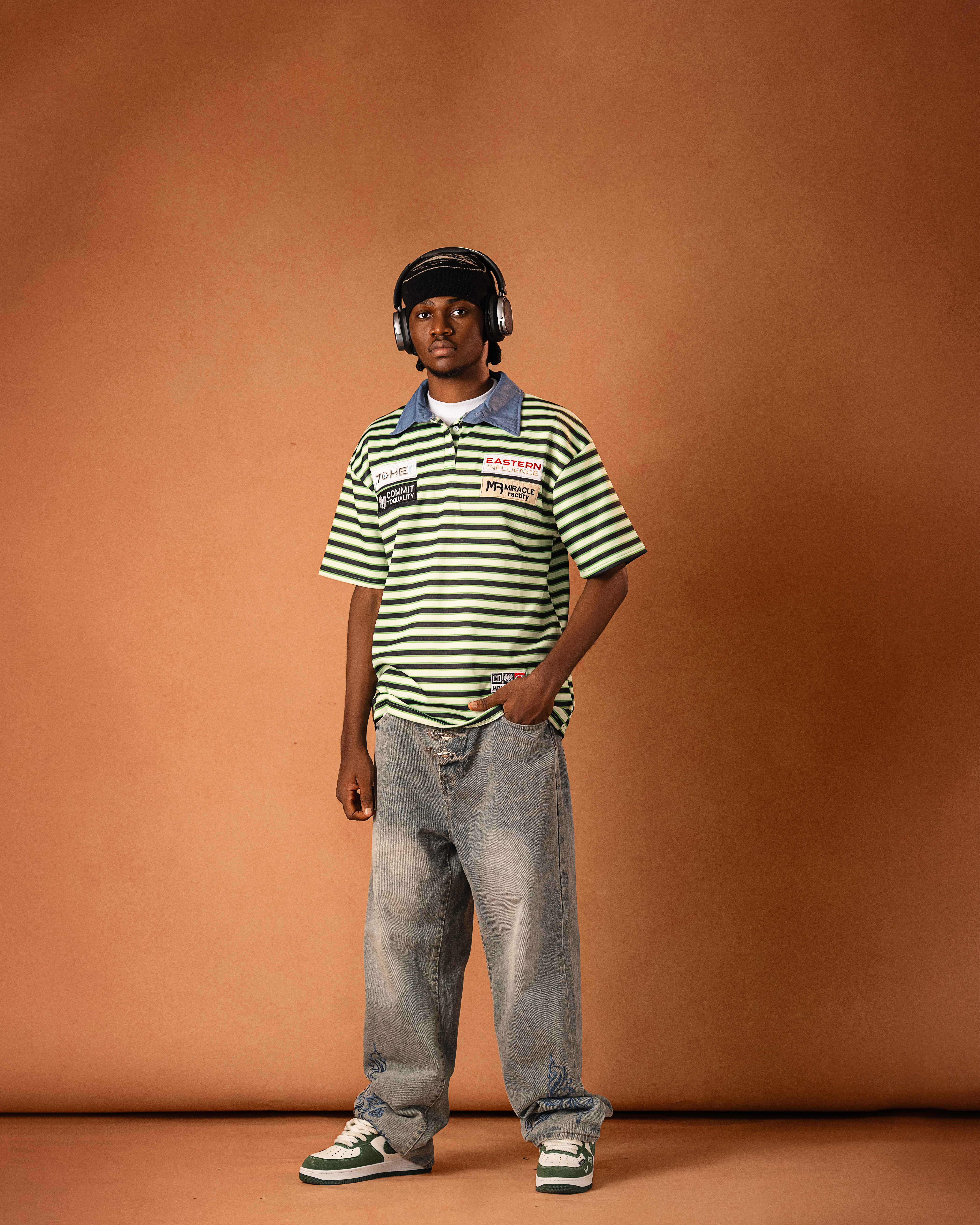 Nueldrick seated indoors in a red tracksuit holding a basketball