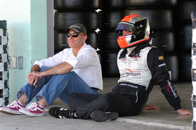 Christian Boudon sitting trackside with a driver in full racing gear