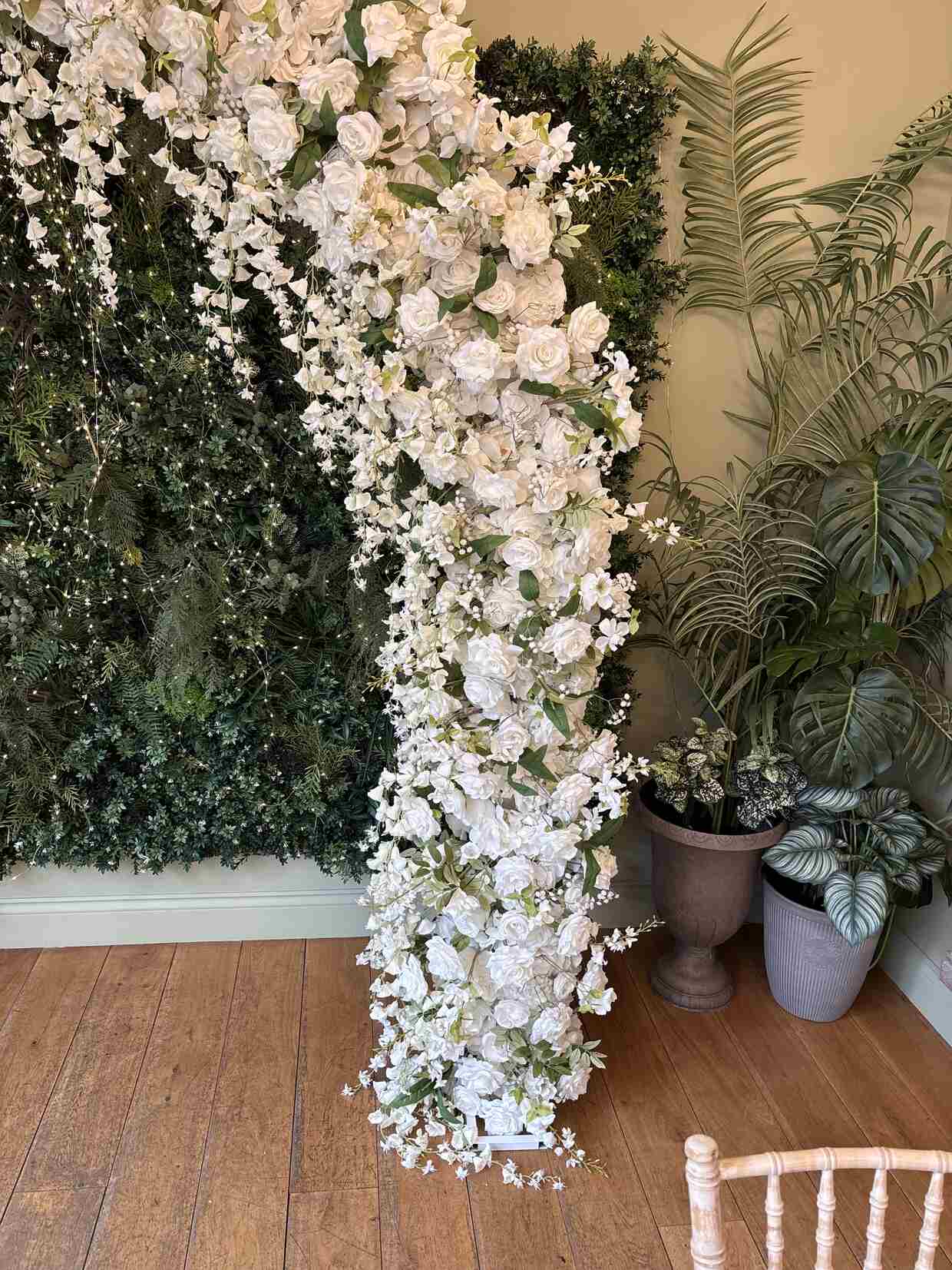 White floral arch pillar with greenery backdrop
