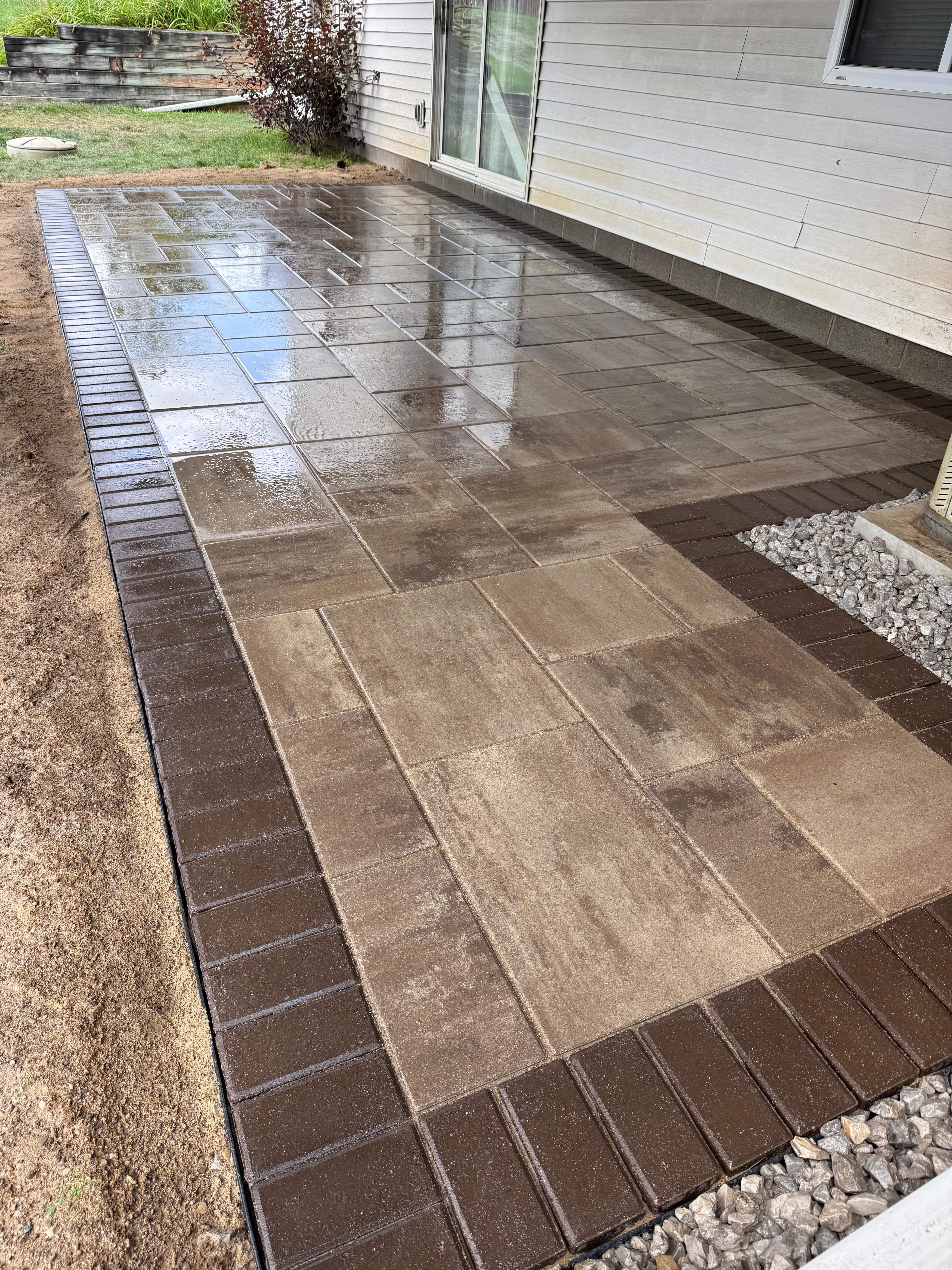 Close-up of wet paver surface showing texture, tone variation, and dark border detail