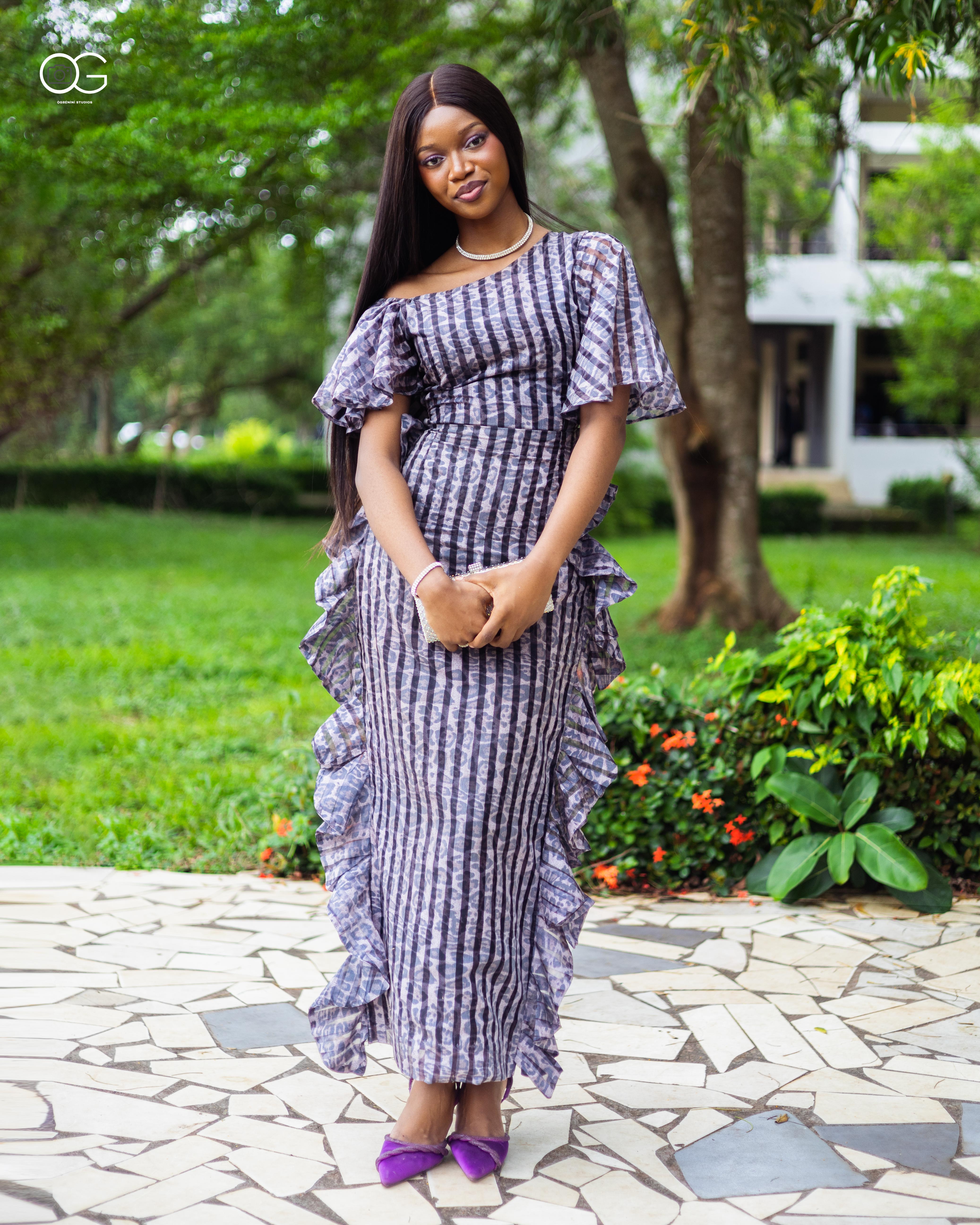 Graduate in a checked dress holding a clutch outdoors