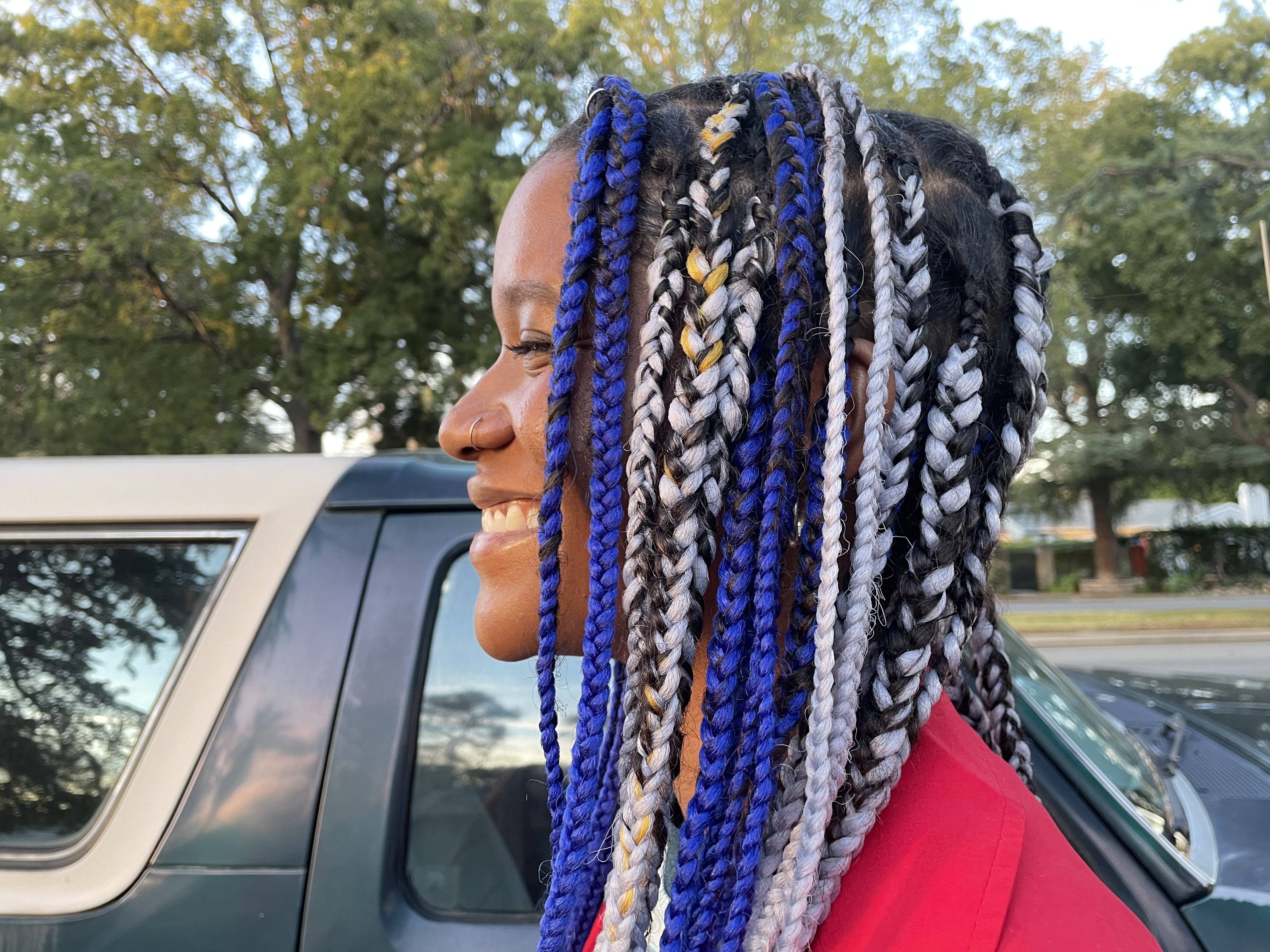 Side profile with blue and gray box braids, smiling outdoors