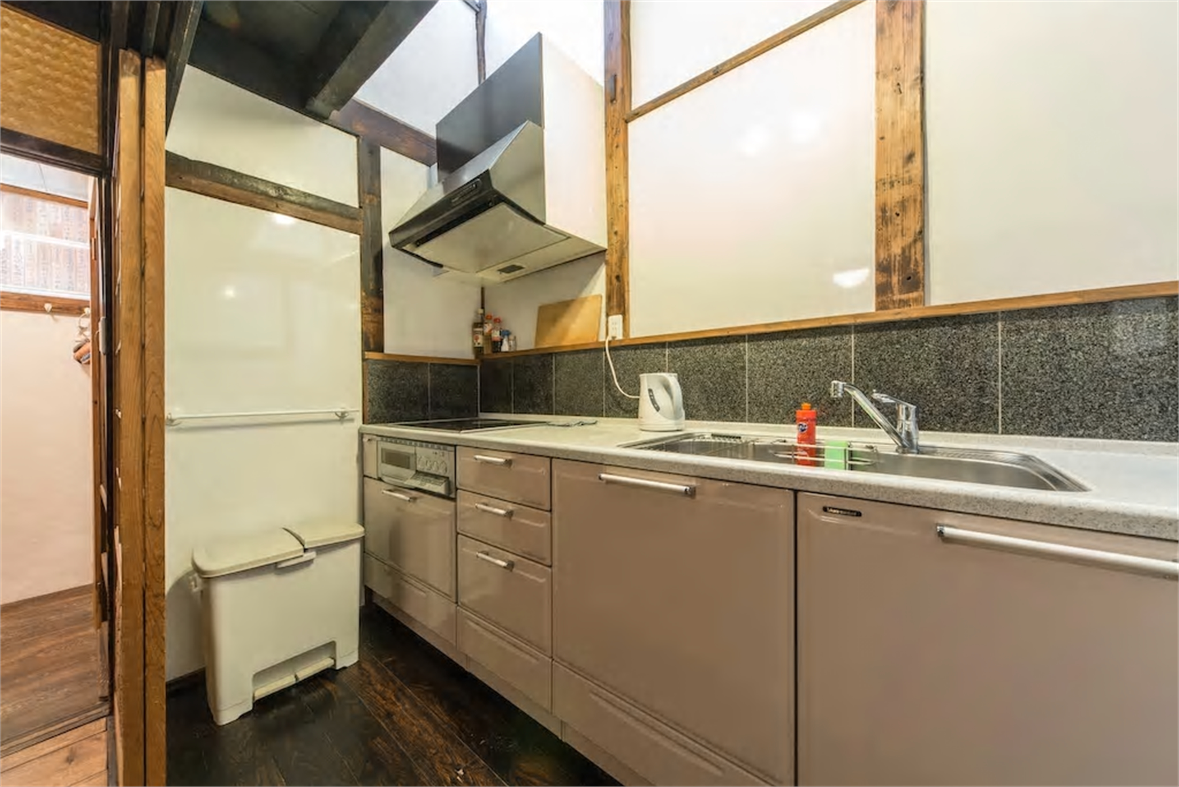 Machiya kitchen with taupe cabinets, granite tile backsplash, dark wooden beams, shoji-style upper walls, stovetop and oven