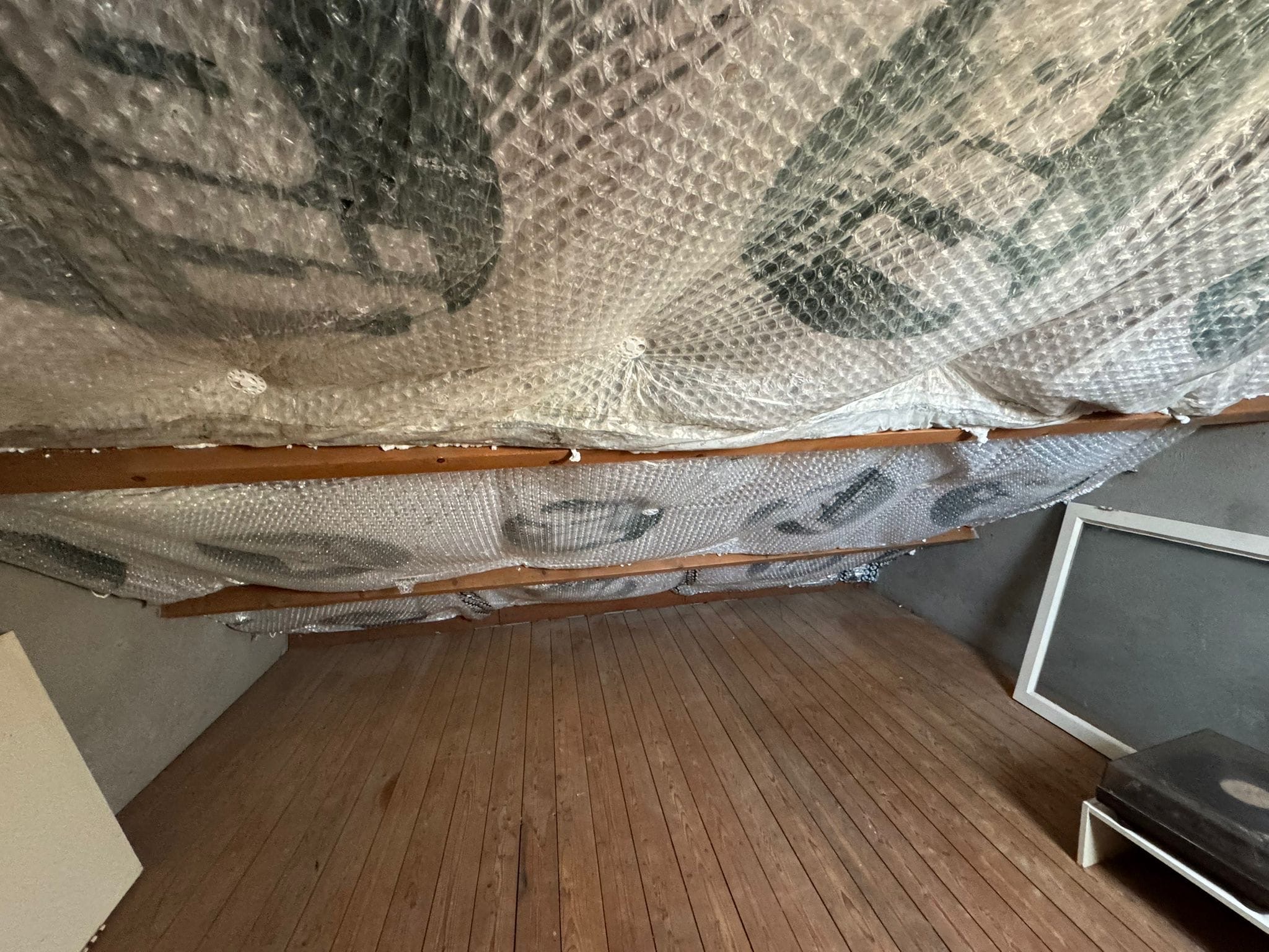 Zolder met isolatiefolie tussen de dakbalken en een houten vloer