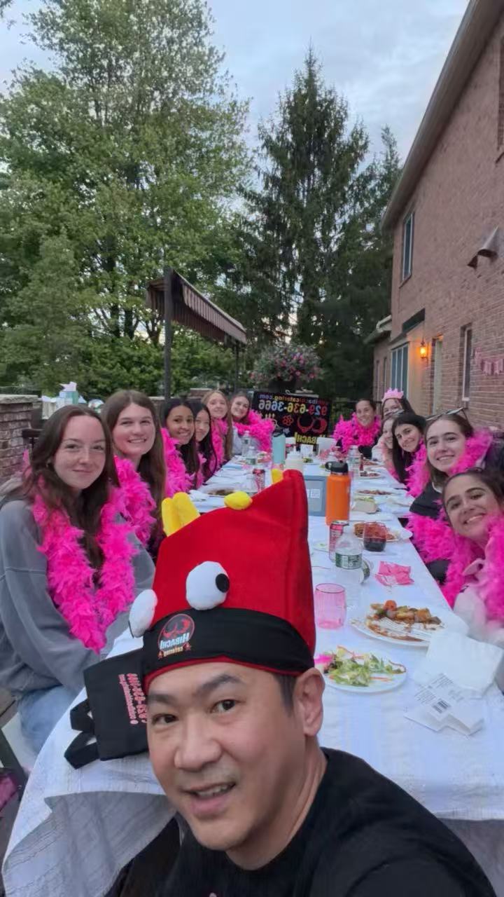 Bachelorette party with chef selfie and guests wearing pink feather boas
