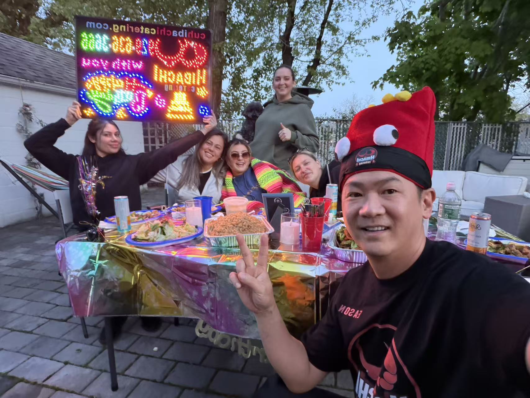 Chef selfie with happy guests holding LED birthday sign at colorful party