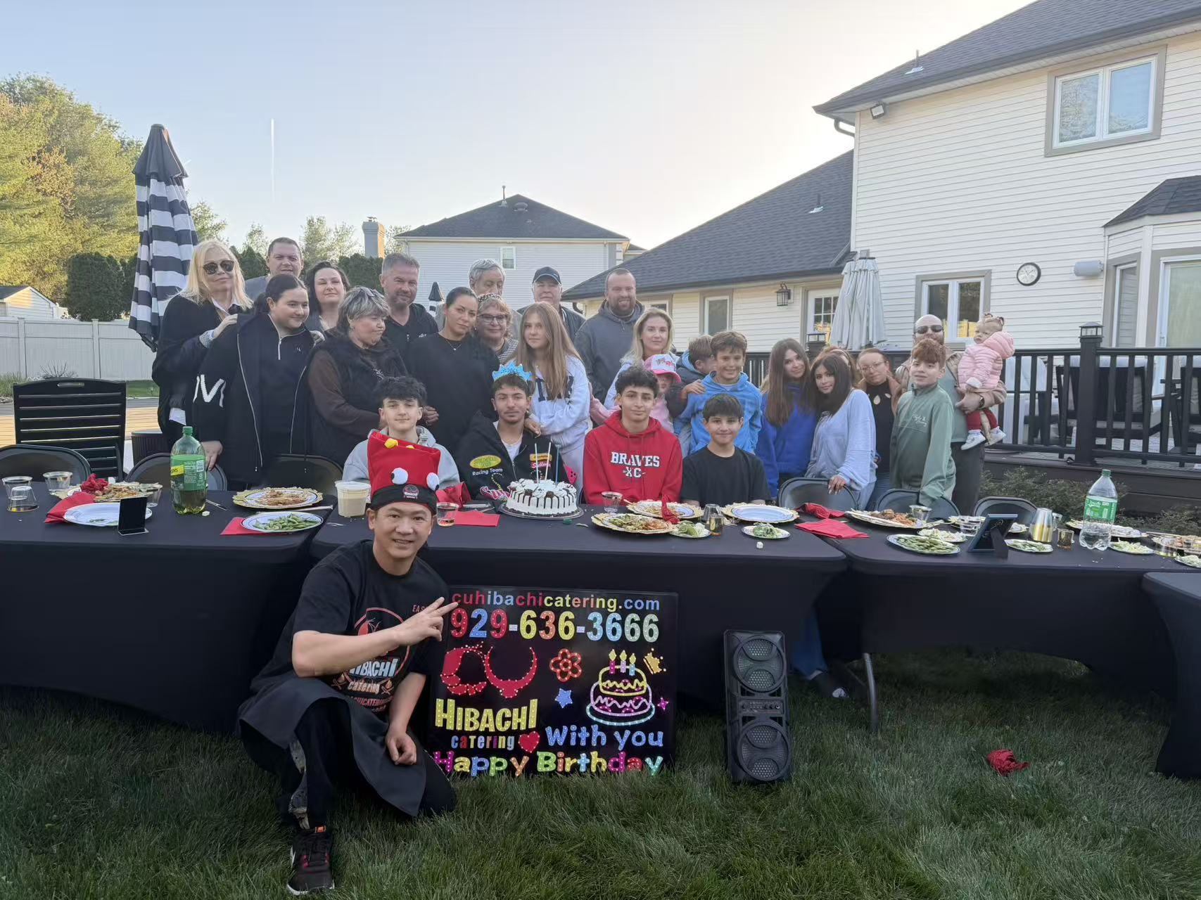 Large family birthday party with LED sign and chef at backyard gathering