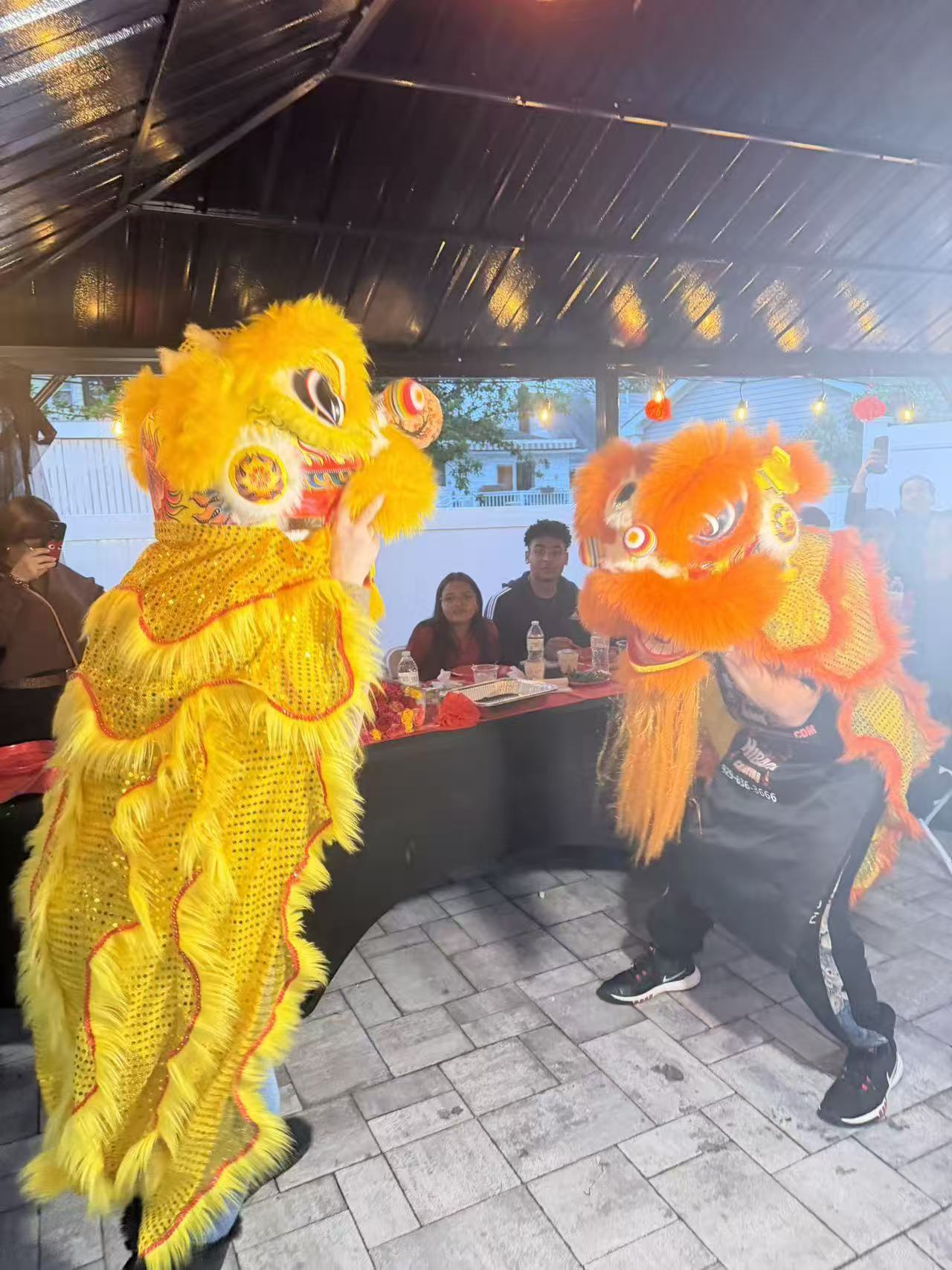 Yellow and orange lion dancers performing at covered patio event