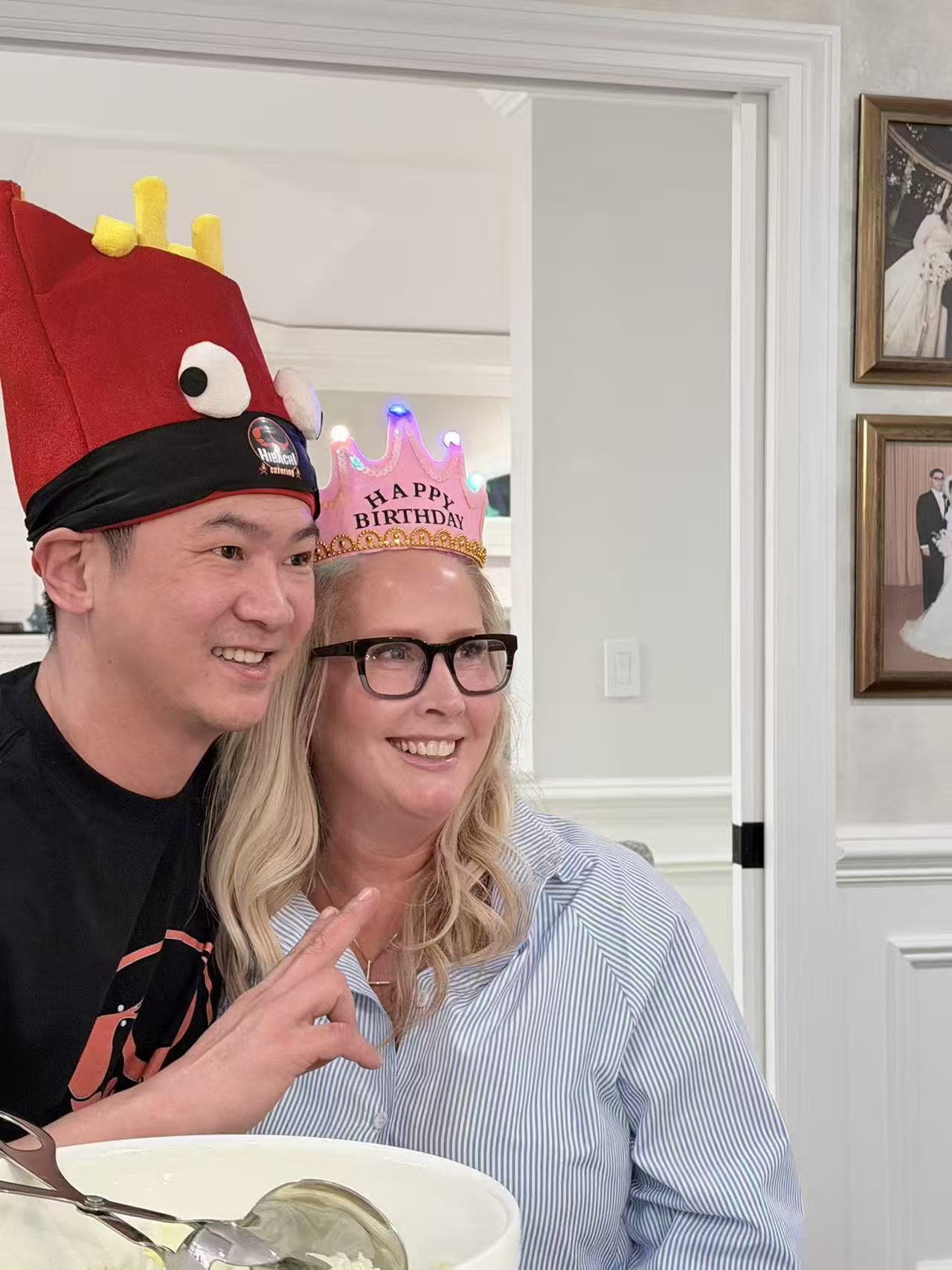 Chef posing with birthday guest wearing light-up pink crown indoors