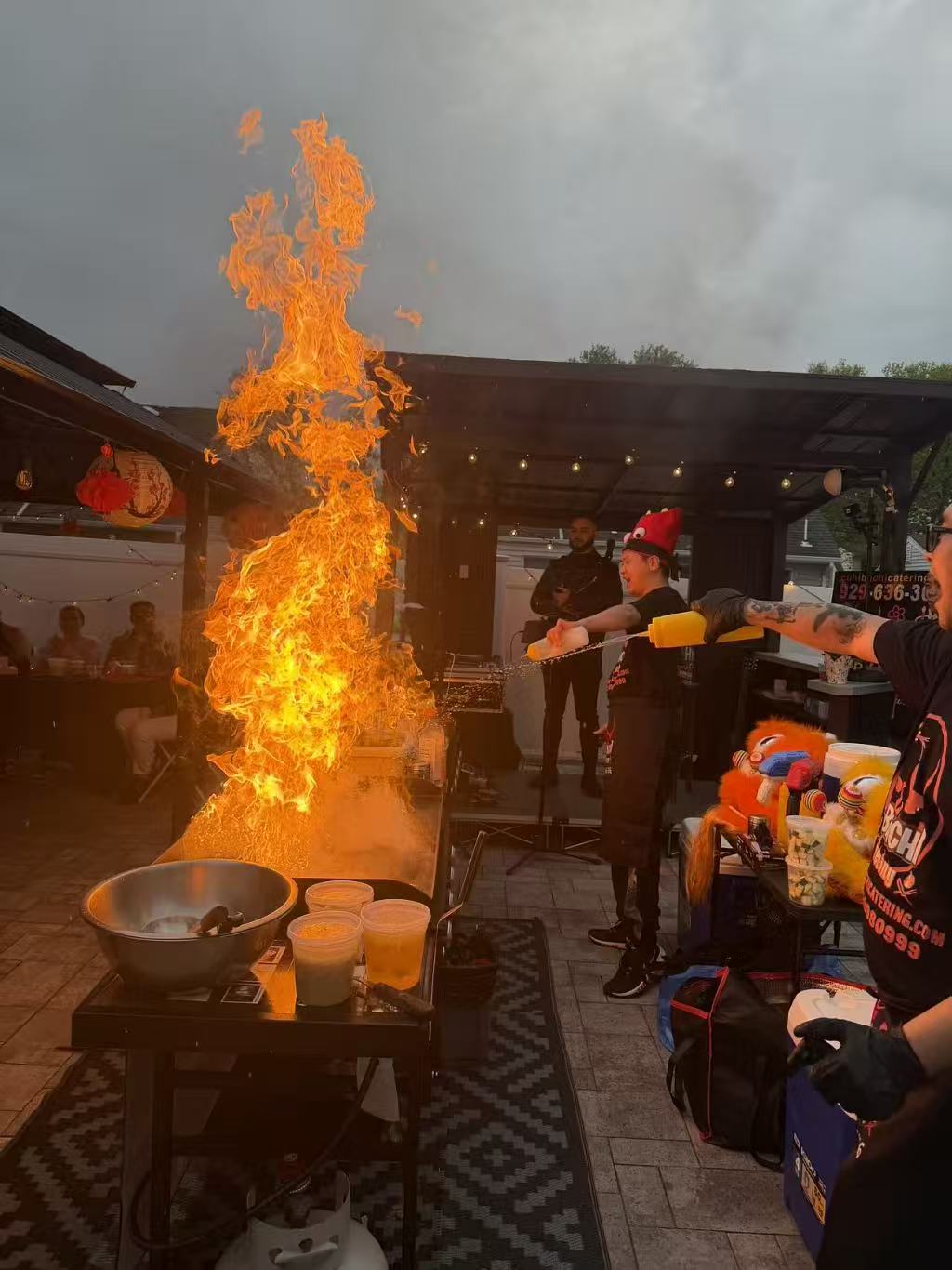 Dramatic fire show with chefs using water guns at covered patio party