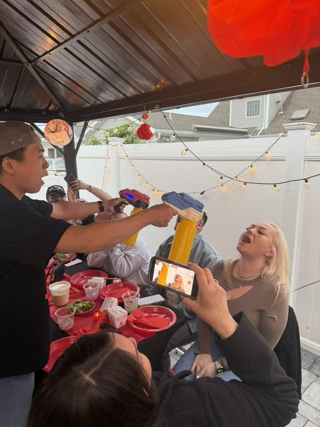 Fun mustard squirt trick with guests laughing at decorated patio party
