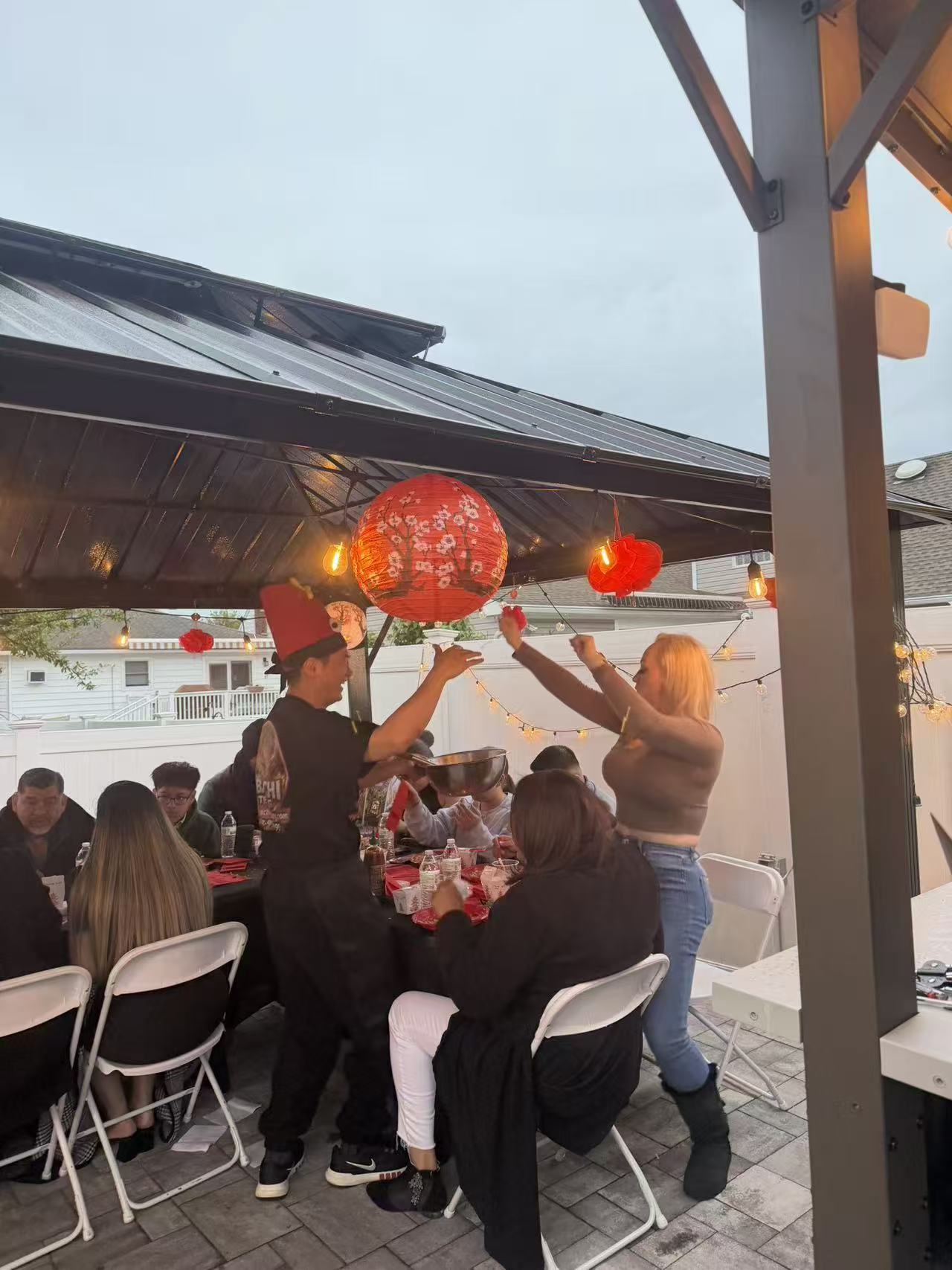 Backyard party with red lanterns and string lights under covered patio