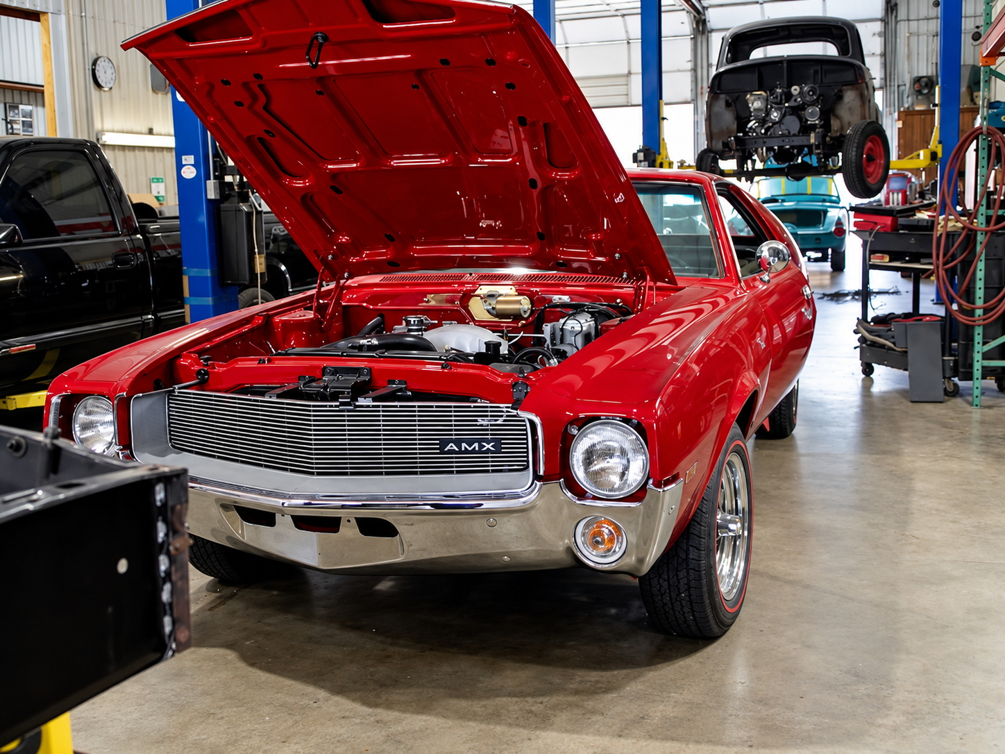 Muscle car vermelho com o capô aberto na oficina