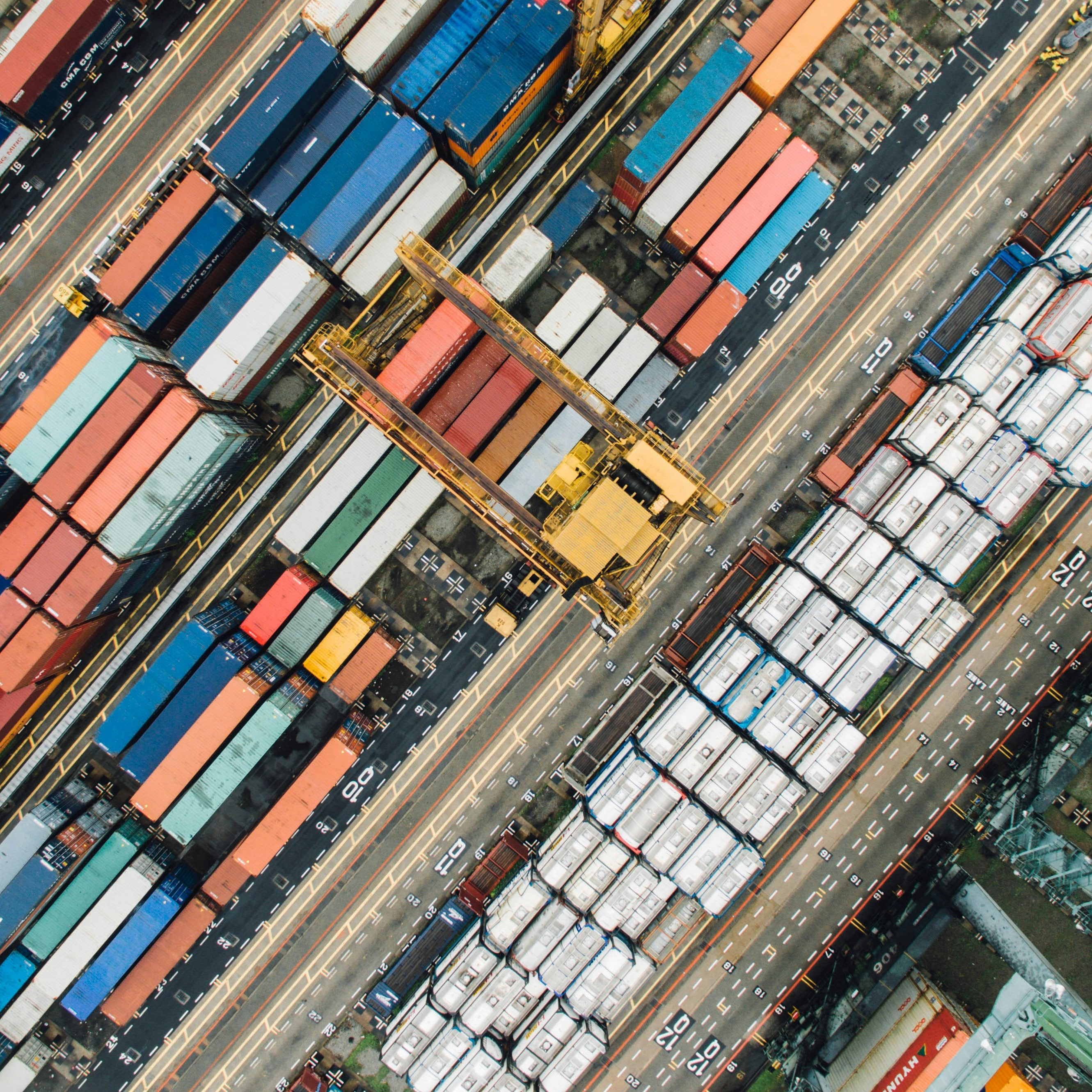 Aerial view of a container yard showing colorful shipping containers arranged in neat rows, symbolizing global trade and supply chain operations