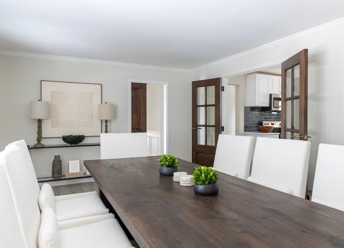 Dining room with white slipcovered chairs, a dark wood table, and custom stained French doors opening to the kitchen
