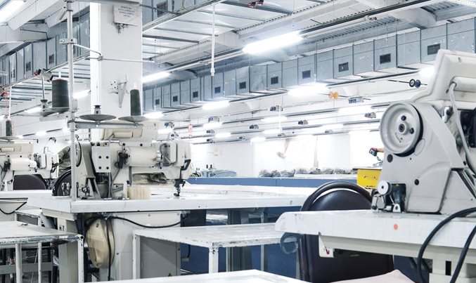Industrial sewing machines arranged across a bright apparel manufacturing floor