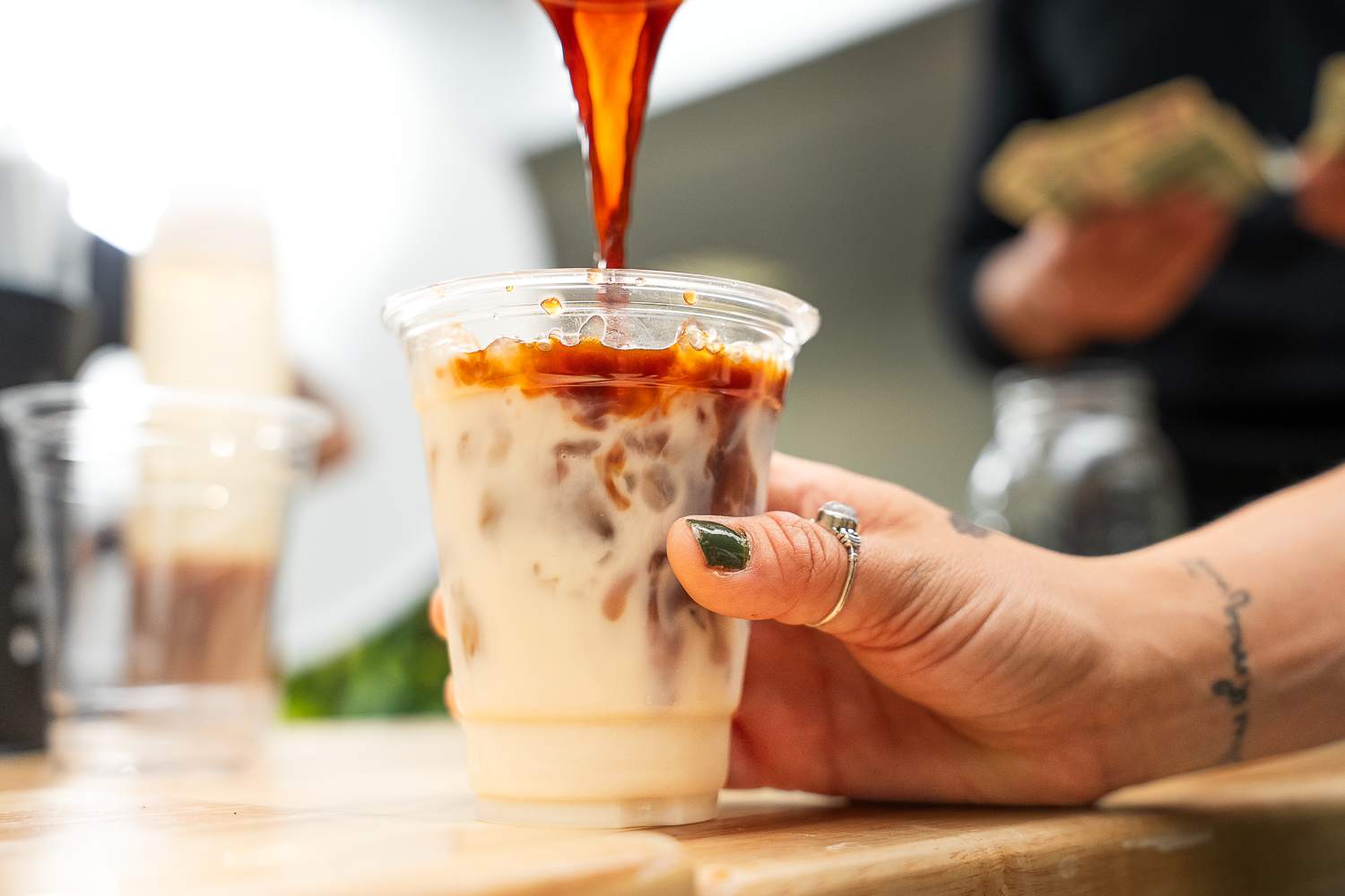 Caramel coffee drink being carefully poured into clear cup