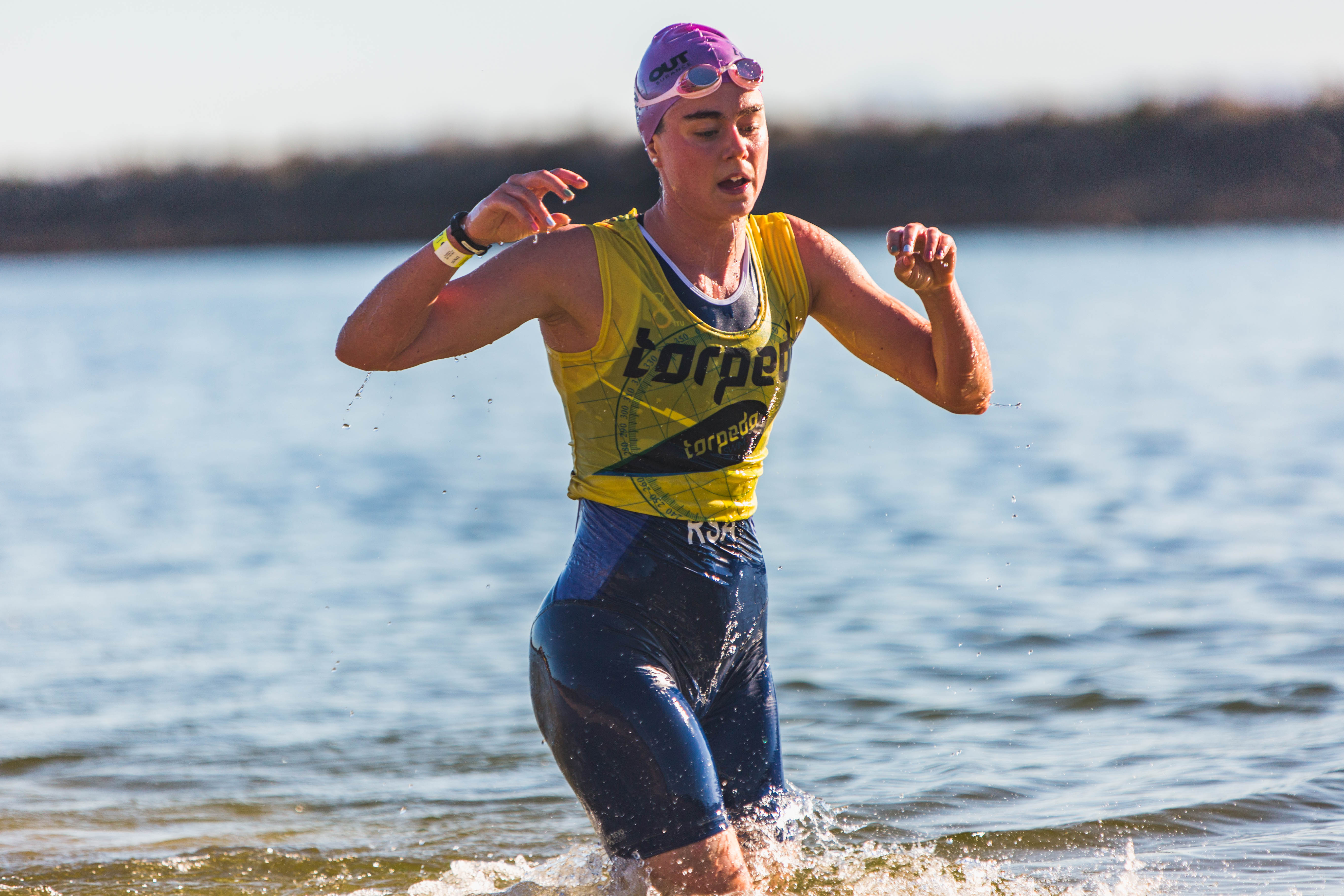 Female athlete running out of dam water in focused transition