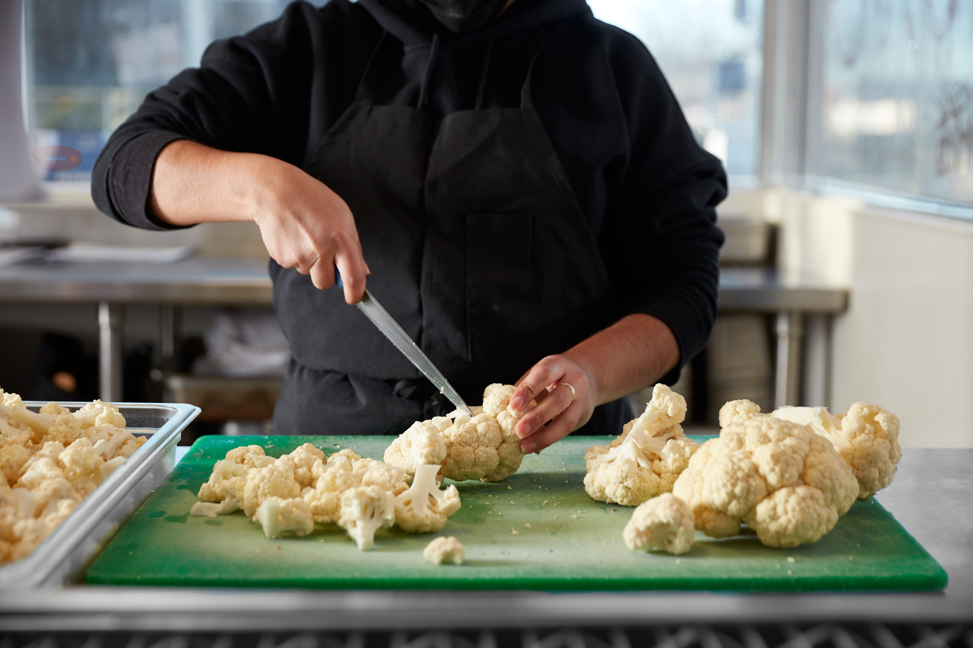 Chef cutting fresh cauliflower into florets during food prep