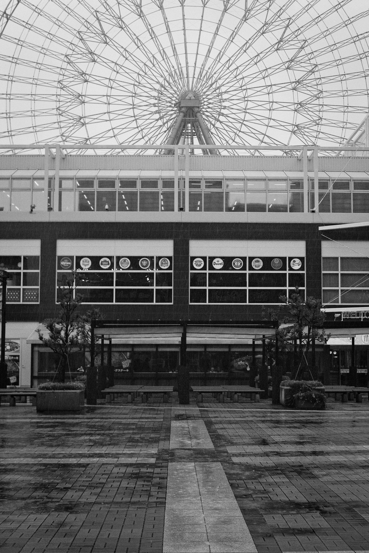 Black and white modern shopping complex with large ferris wheel dome structure brick courtyard