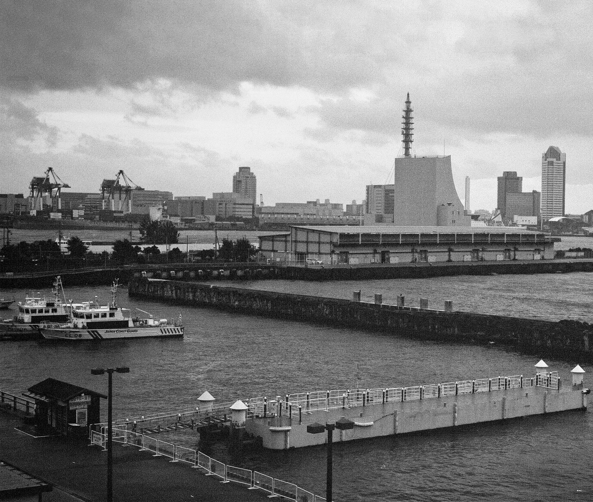 Black and white harbor port view with coast guard vessels industrial skyline dramatic sky