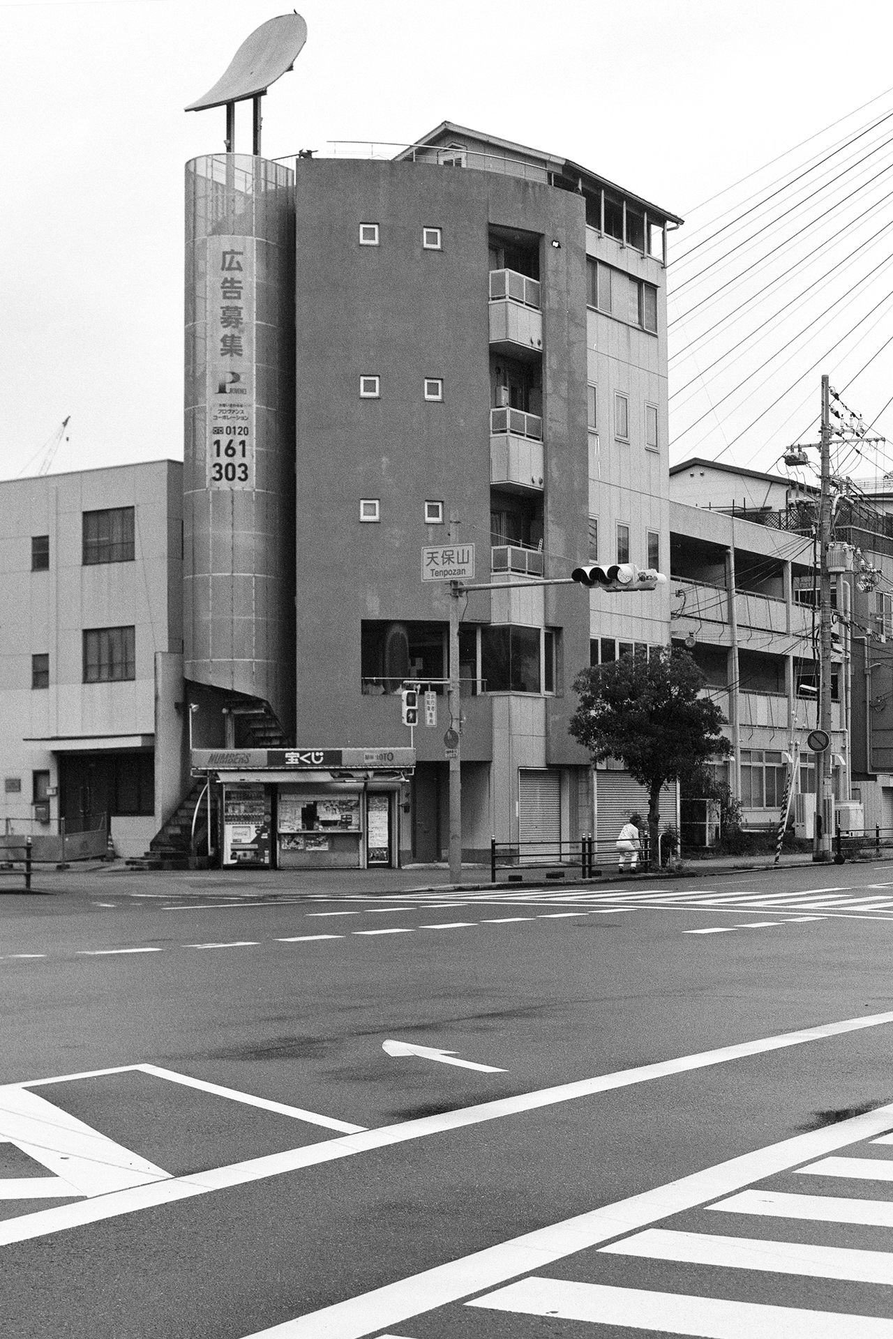 Black and white distinctive cylindrical building with satellite dish corner intersection traffic markings