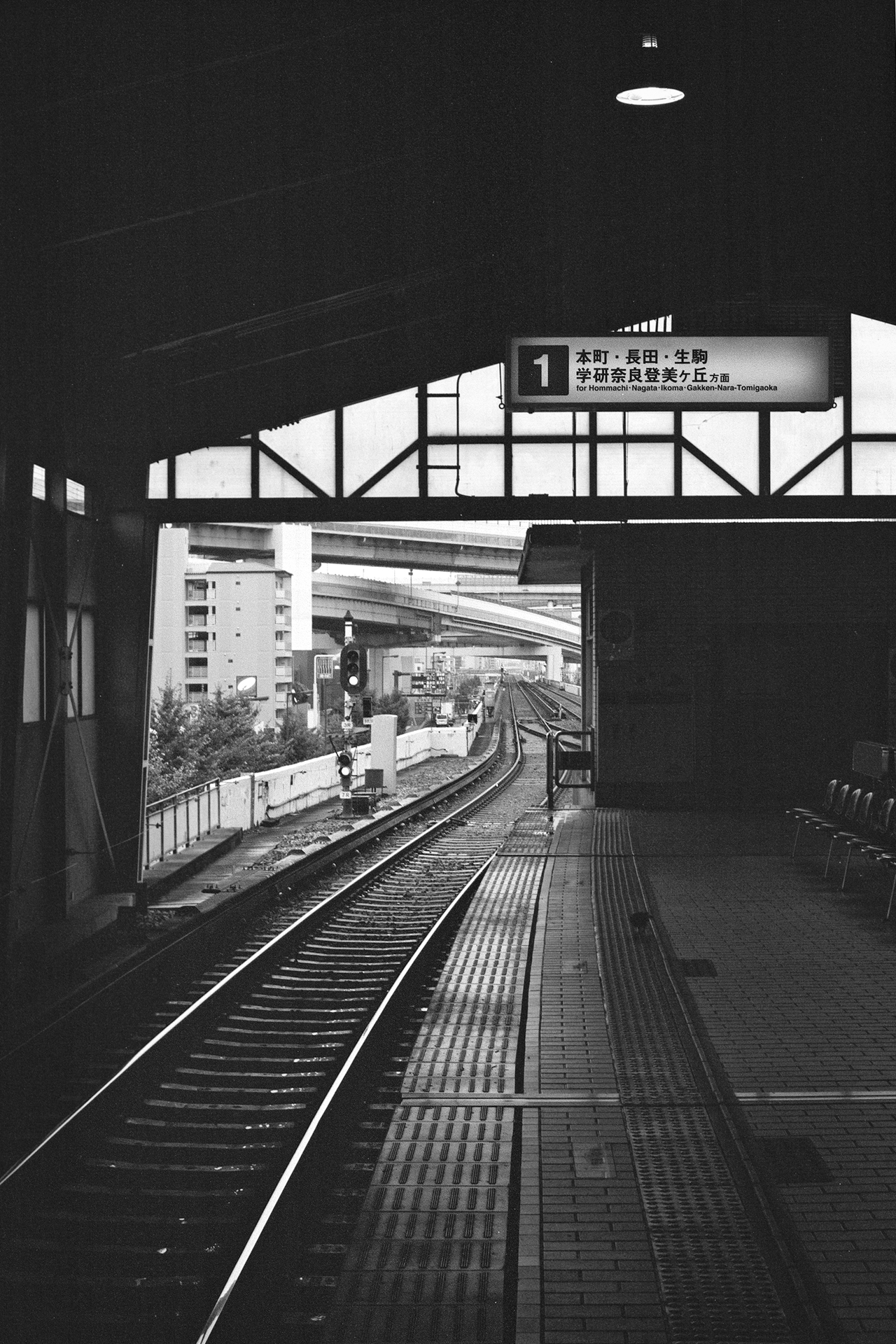Black and white train station interior with track curving away Japanese destination signage