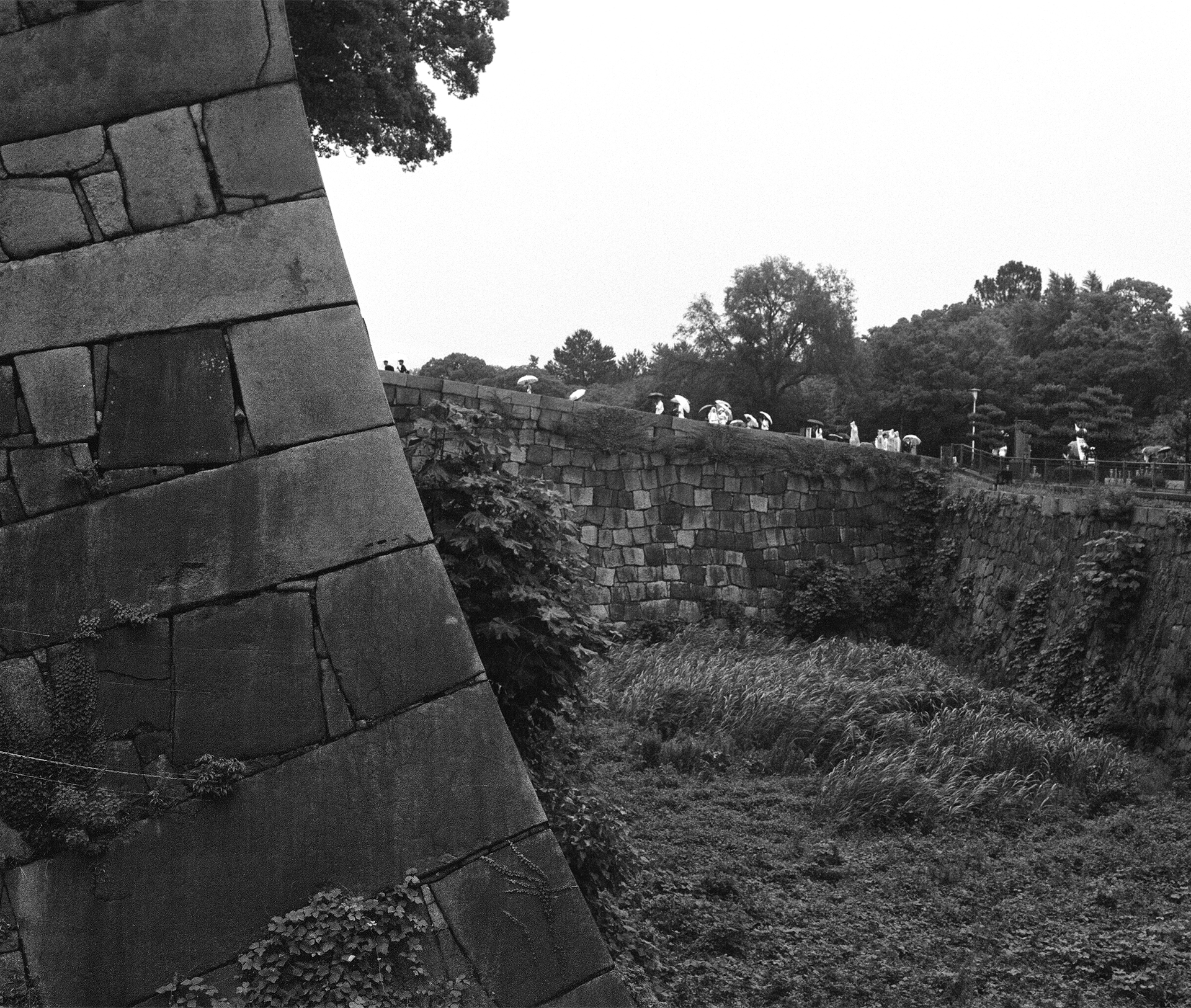 Black and white castle walls along moat with watchtower modern buildings in misty background