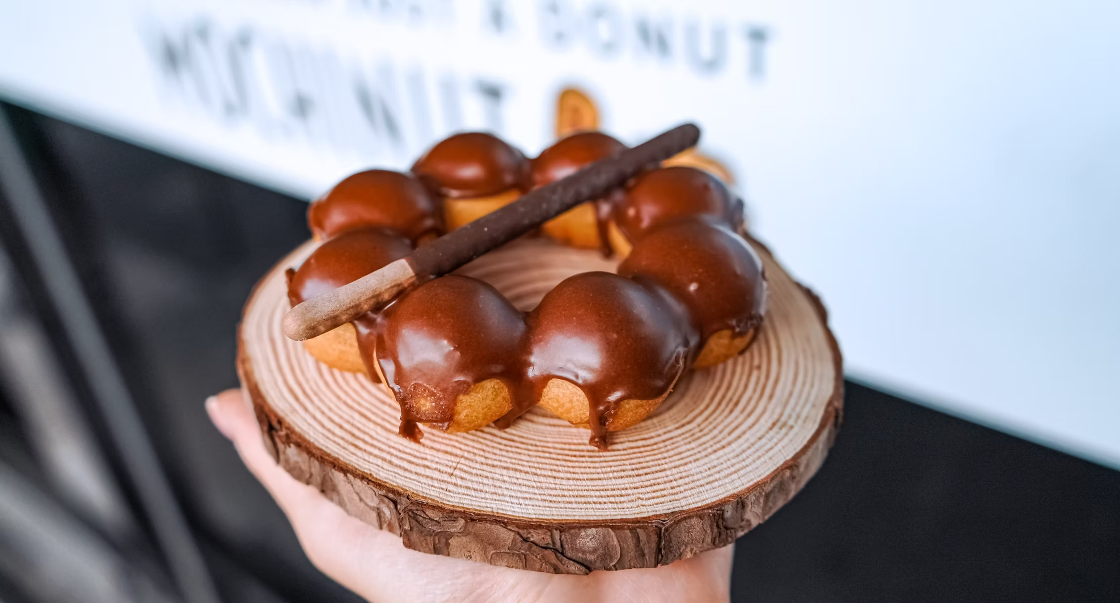 Chocolate-covered mochi donut on wooden plate