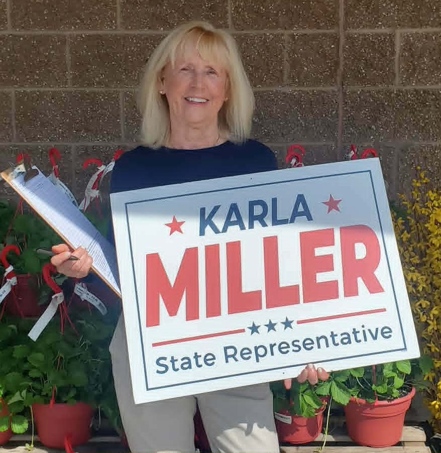 Karla Miller collecting signatures with clipboard and campaign sign