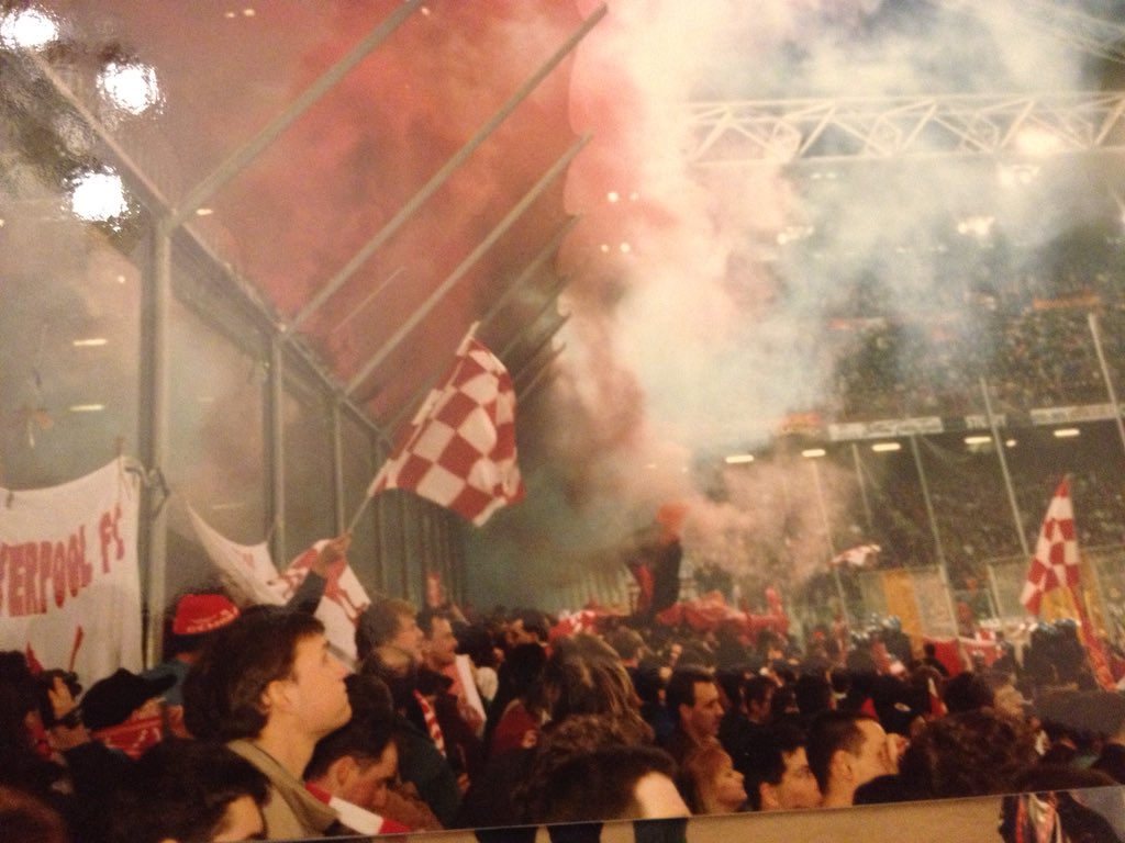 The Kop with red and white checkered flags and flares