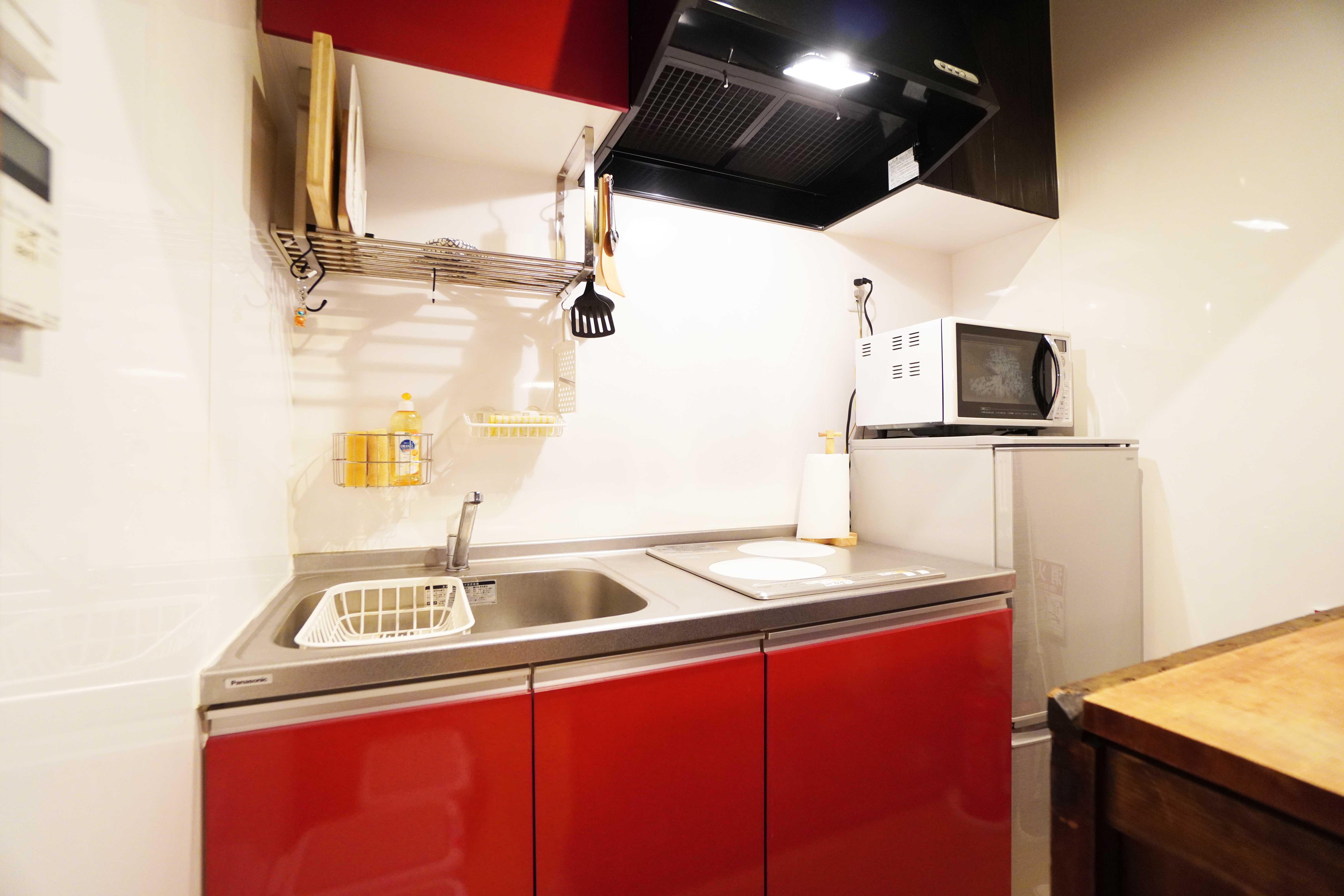 Retro-style kitchen with bold red cabinets, stainless steel countertops, and IH cooktop