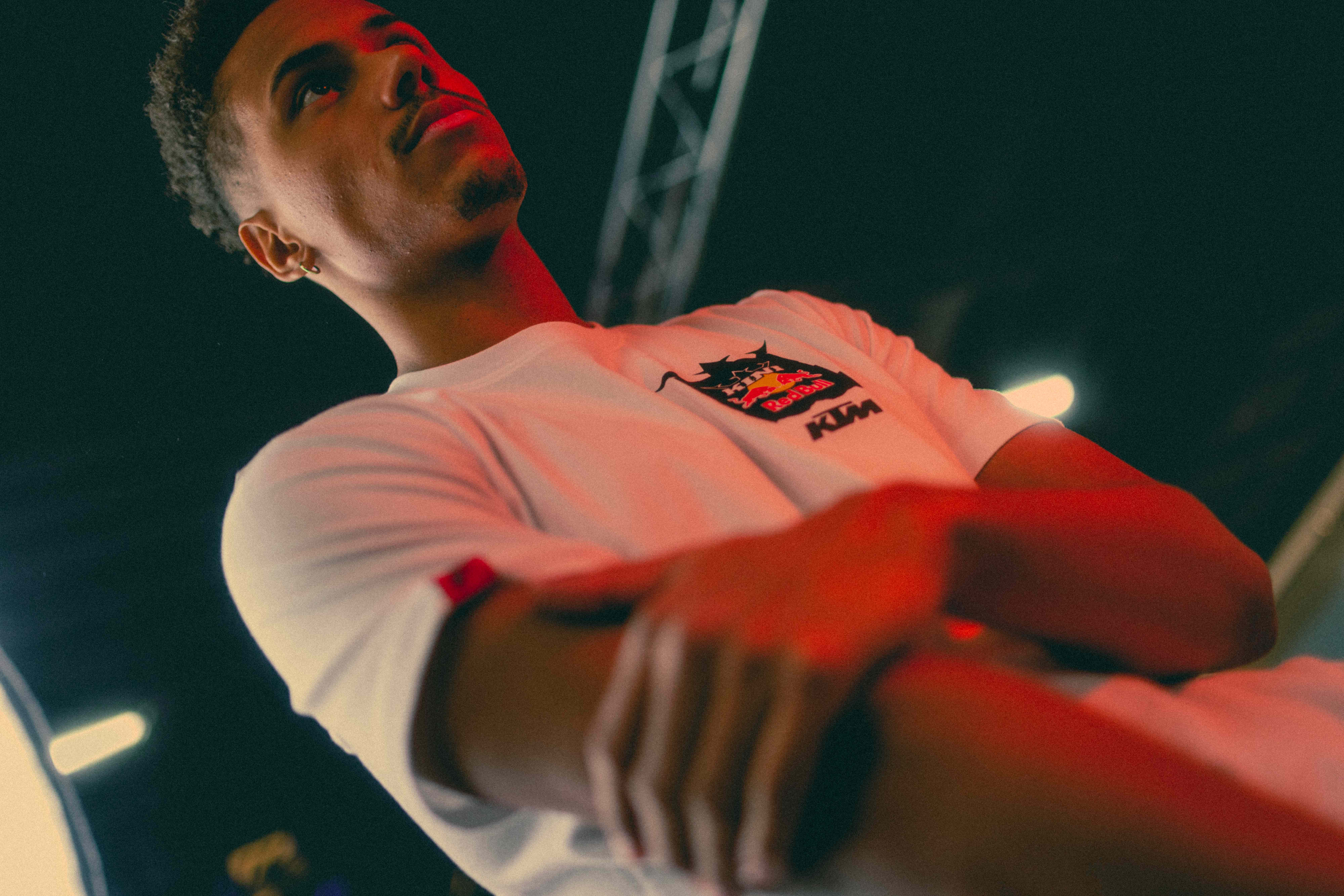 Man in a white Red Bull KTM t-shirt under dramatic red event lighting at night