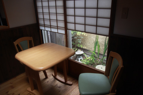 Cozy breakfast nook with small wooden table and chairs beside shoji screens overlooking the tsuboniwa garden