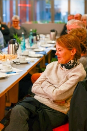 Frau mit verschränkten Armen hört aufmerksam zu – Kulturcafé im Bonni