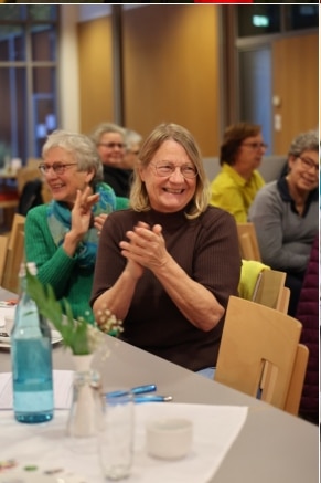 Frau lacht herzlich bei einer Veranstaltung im Kulturcafé