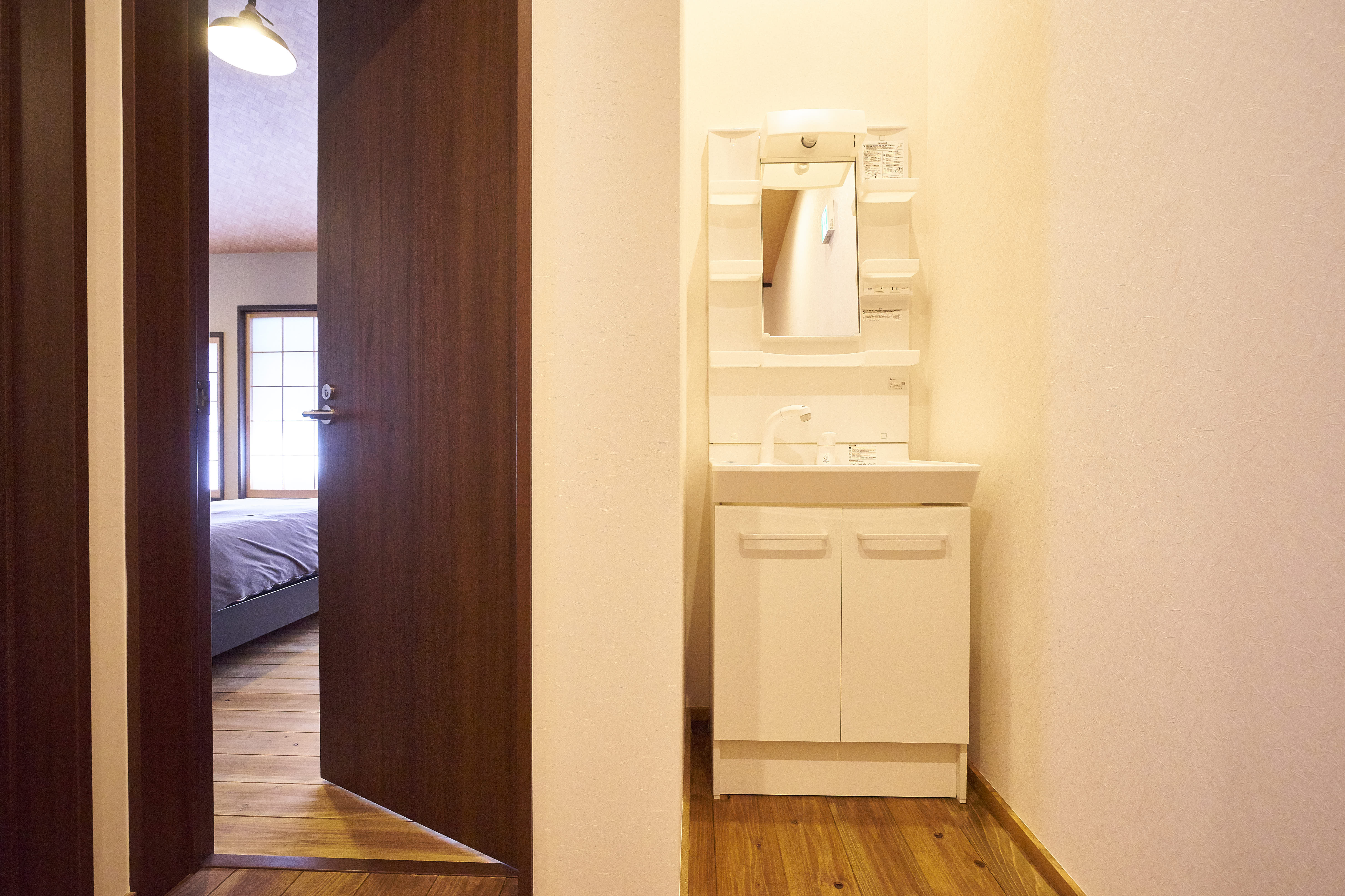 Hallway with vanity washbasin and view into bedroom with wooden floors and shoji screens