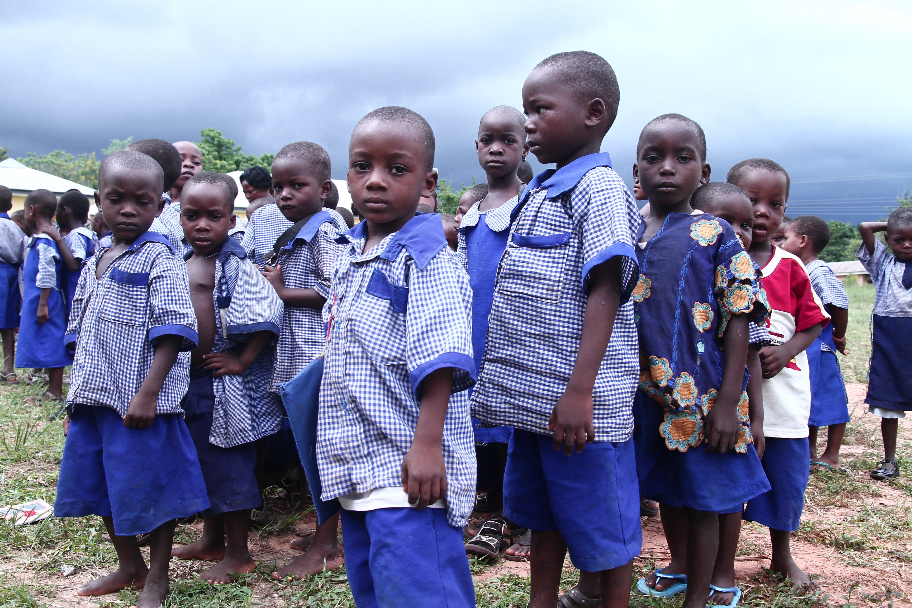 Children in blue uniforms under dramatic sky