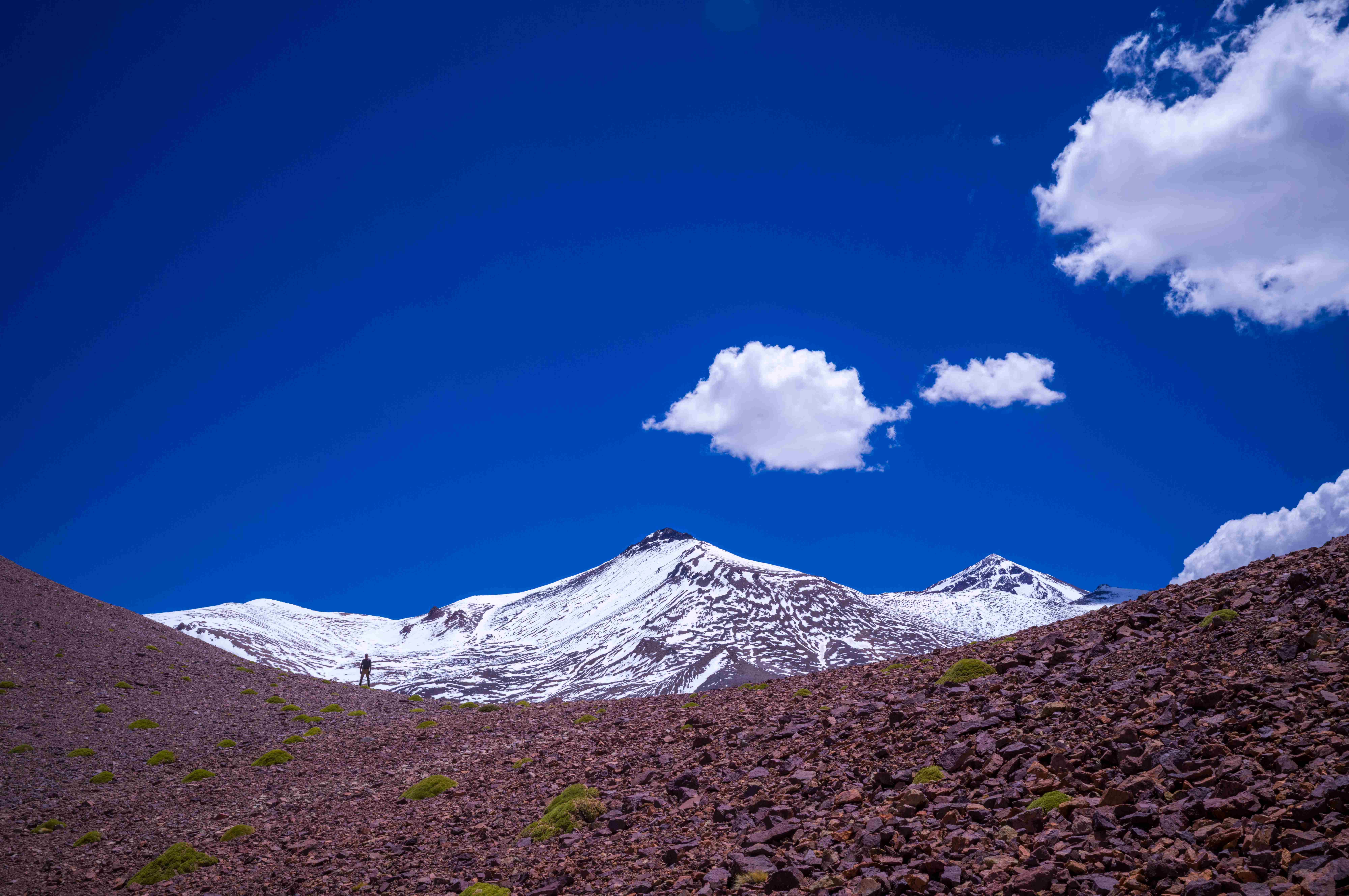 Caminante en terreno rocoso con cumbres nevadas al fondo