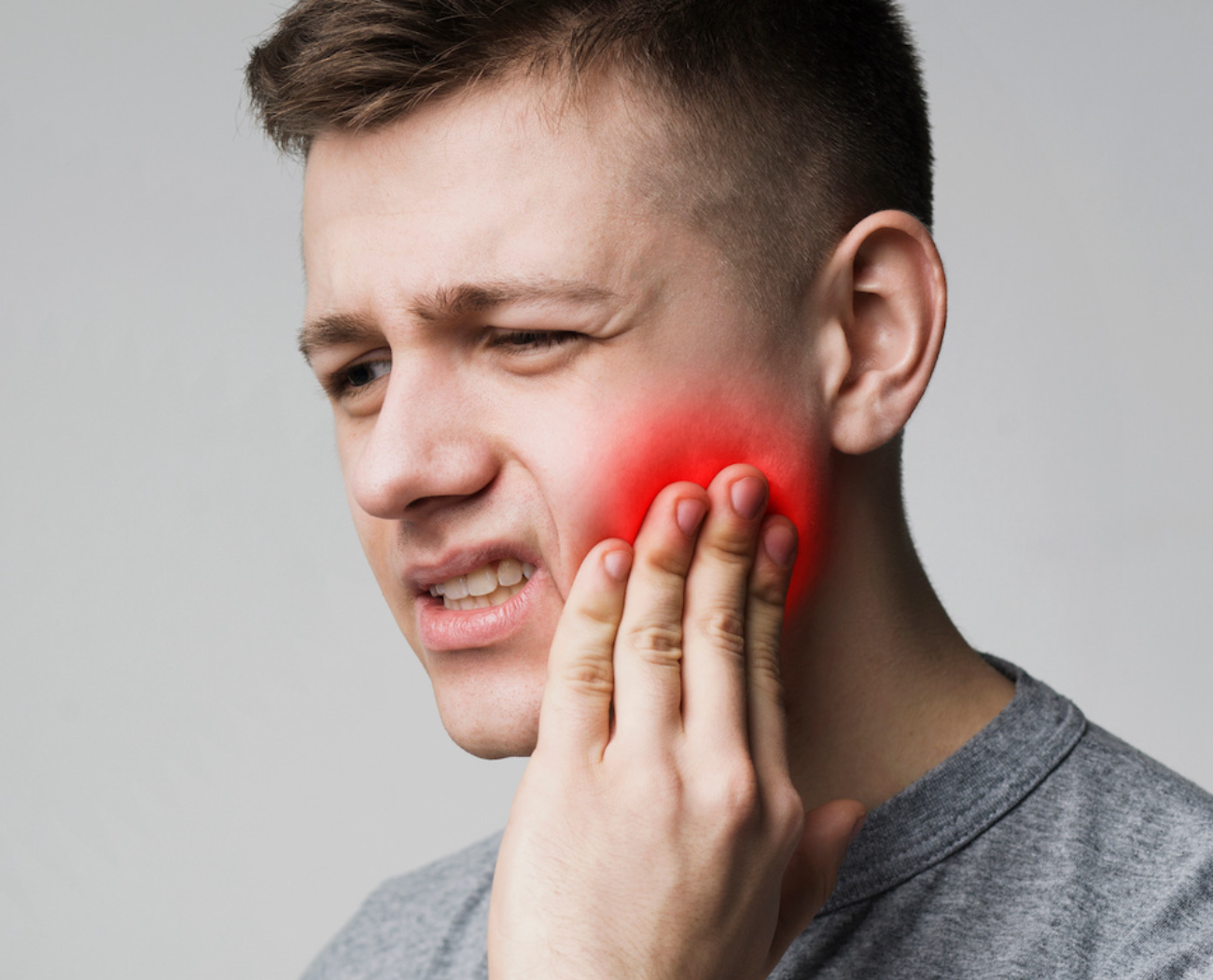 Man experiencing dental pain holding his jaw