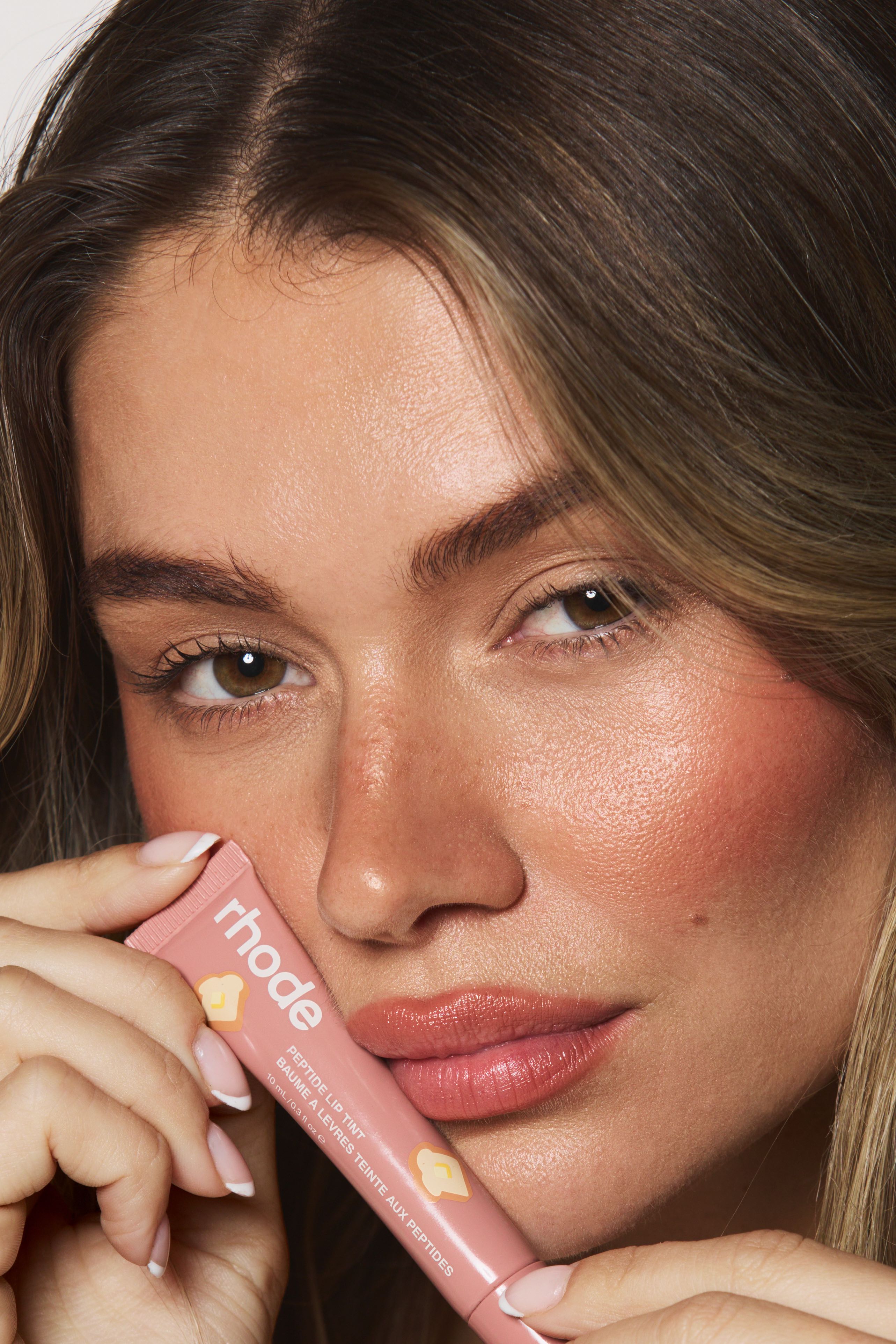 Mollie closeup holding Rhode lip tint near face