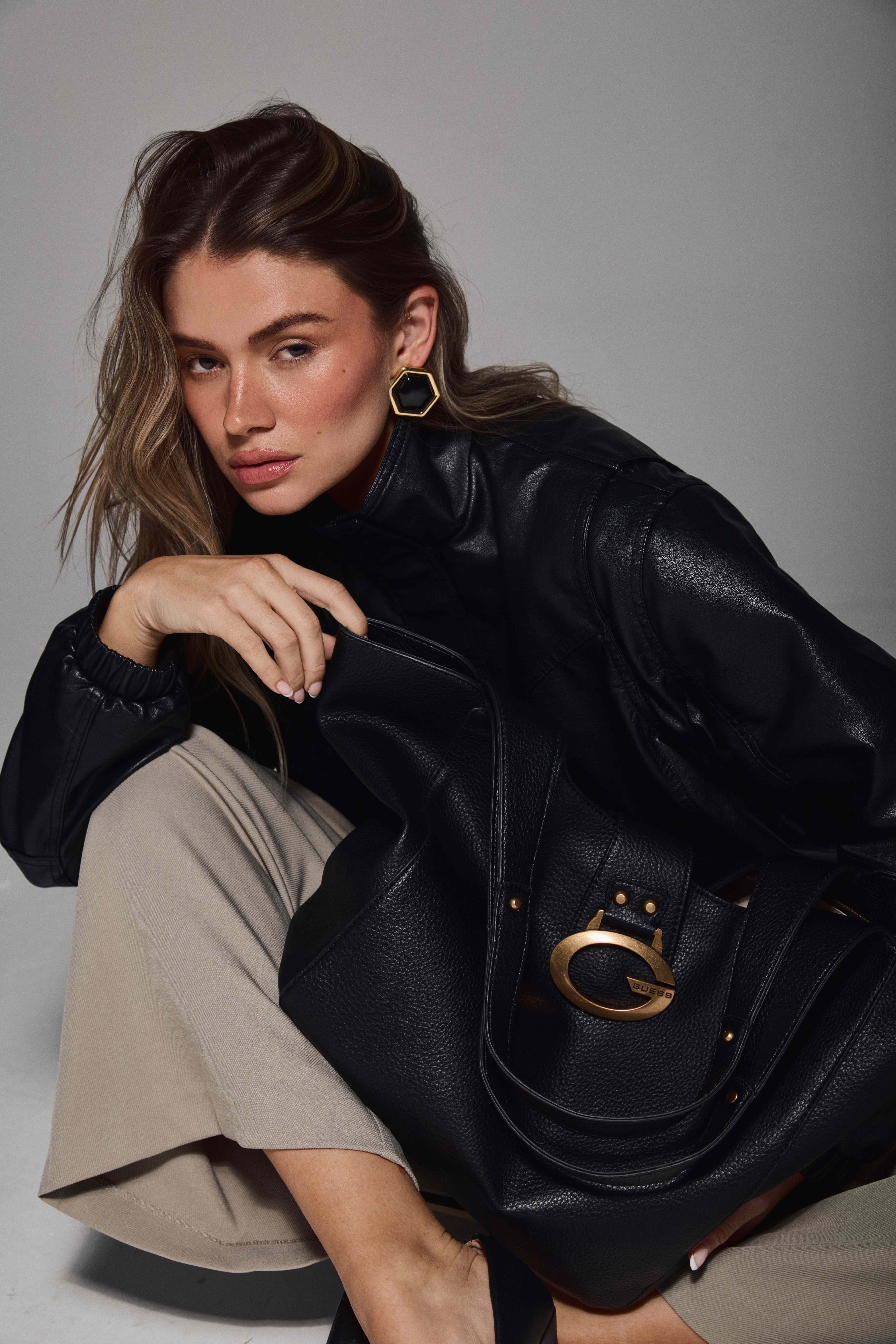 Mollie seated with GUESS handbag black leather jacket