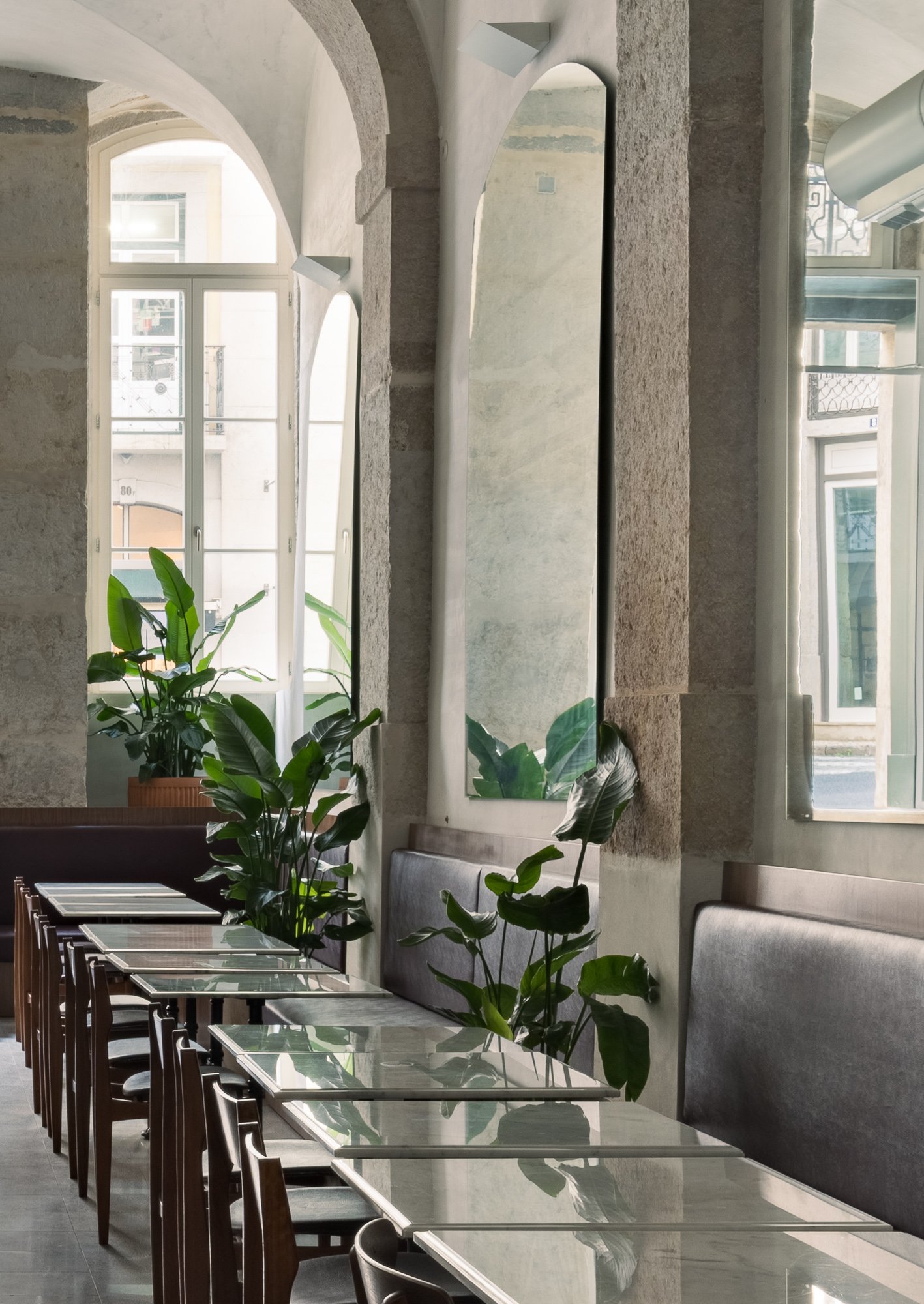 Side view of dining area with glass tables and leather banquettes under arched windows