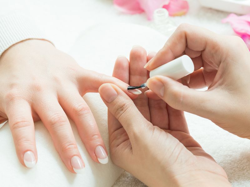 Nail technician applying polish to a client's fingernail.