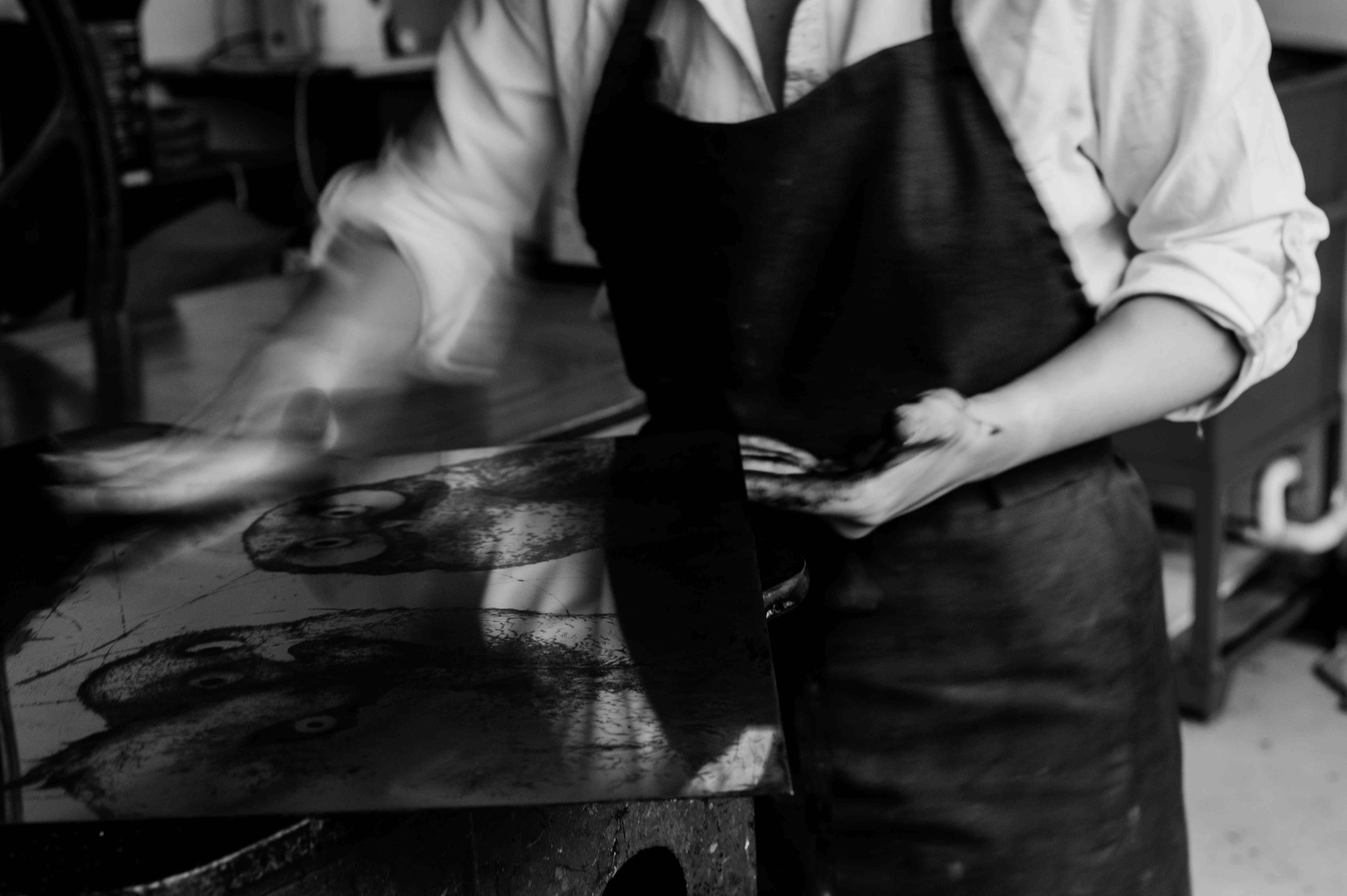The artist wiping ink from a copper plate with a tarlatan.