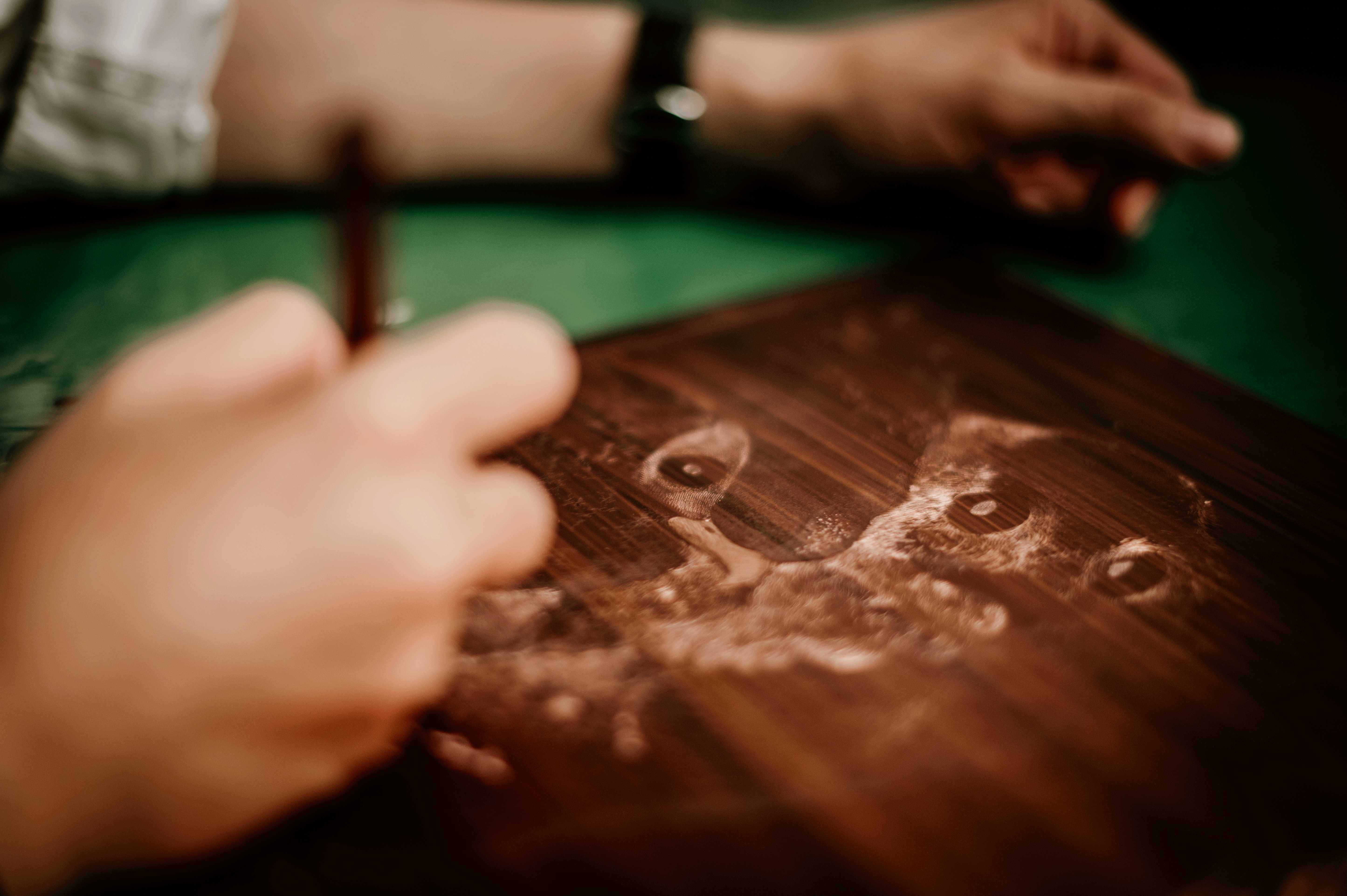 A hand reaching toward an inked owl plate in low light.