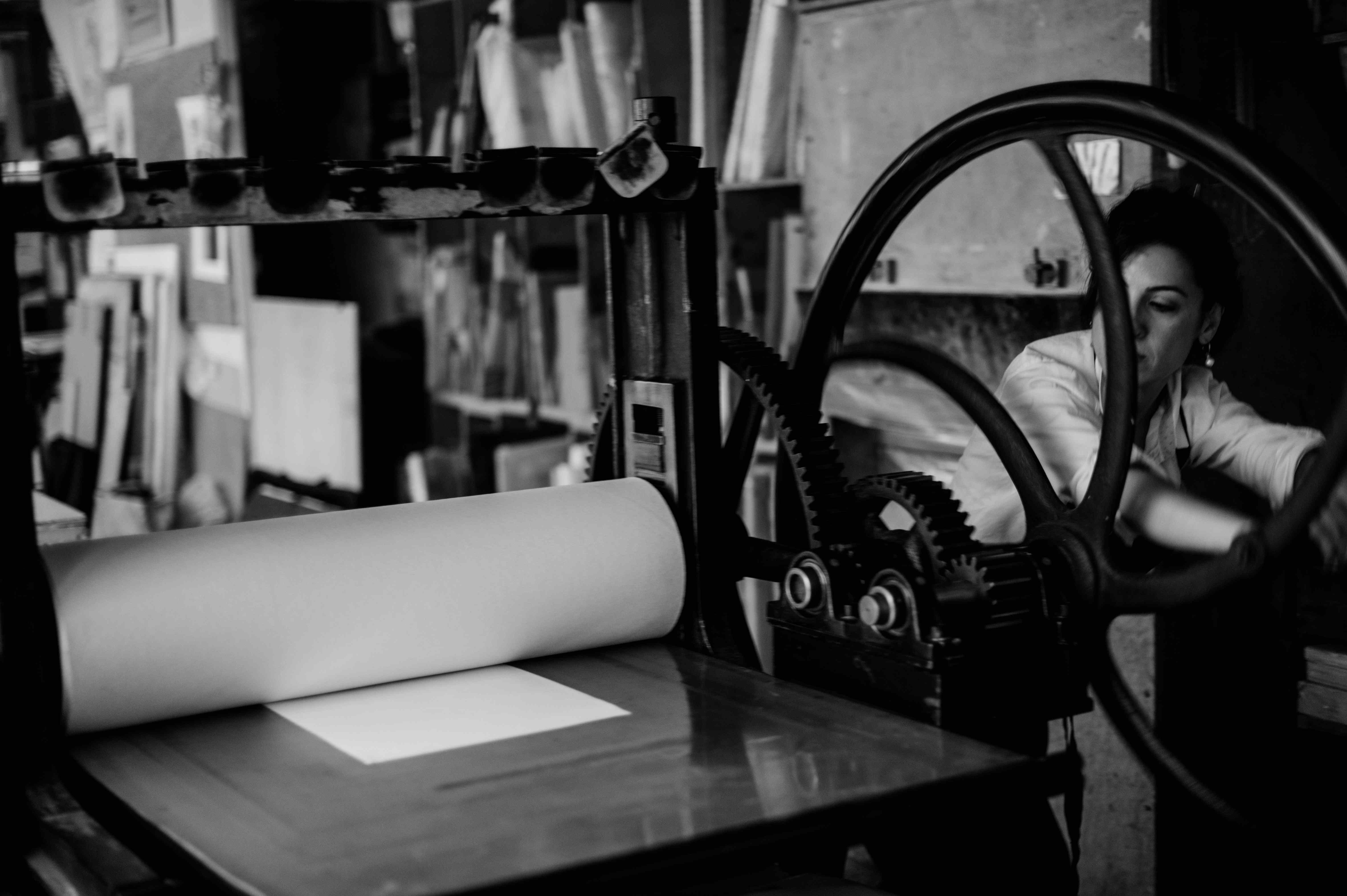 The artist seen through the great wheel of the printing press.