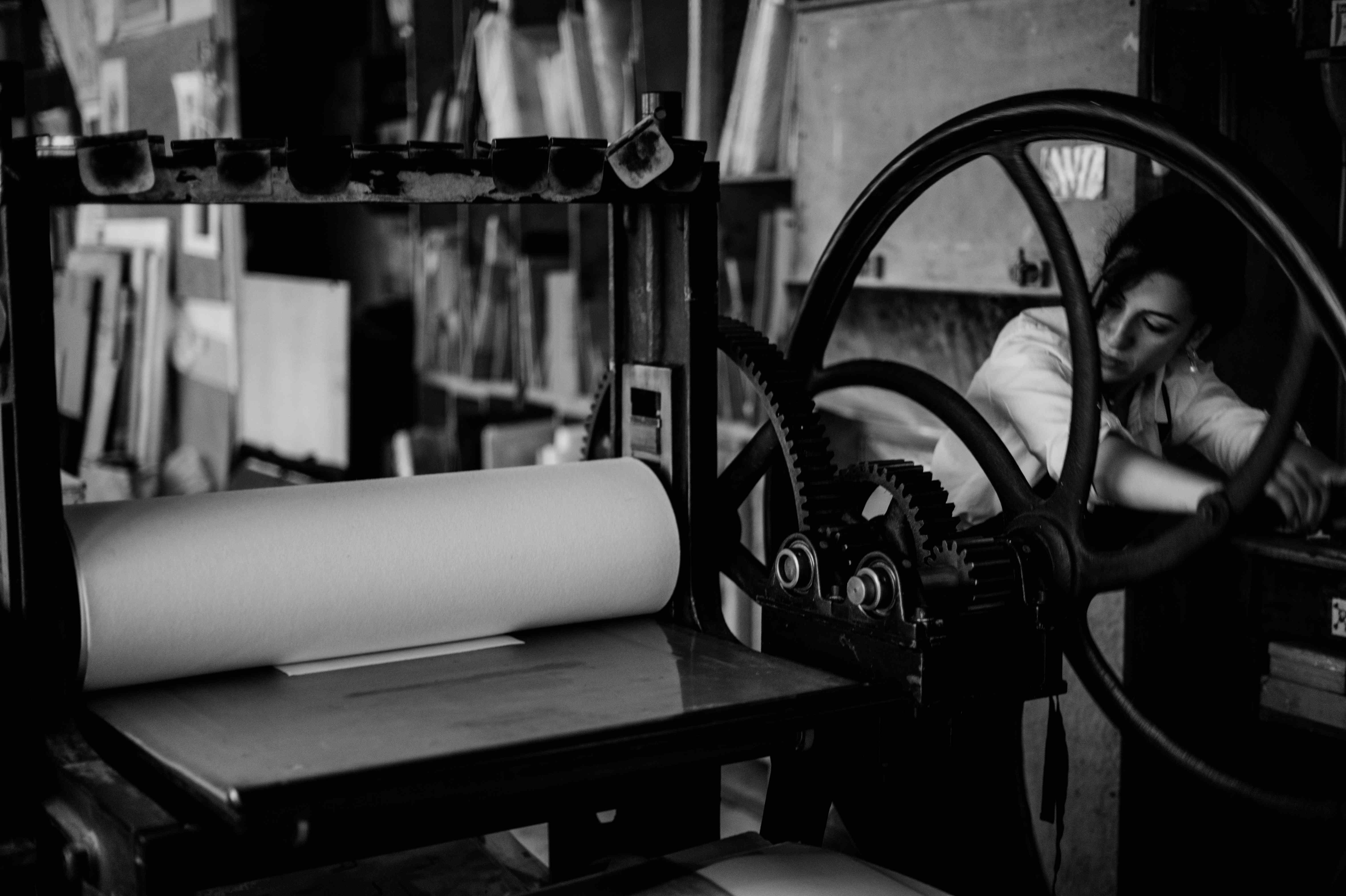 The artist turning the wheel of an antique intaglio press.