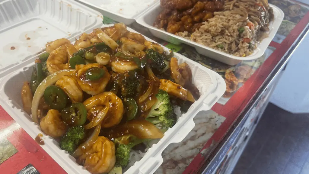 Authentic food from Mark's Kitchen showing shrimp with broccoli and peppers in a takeout container