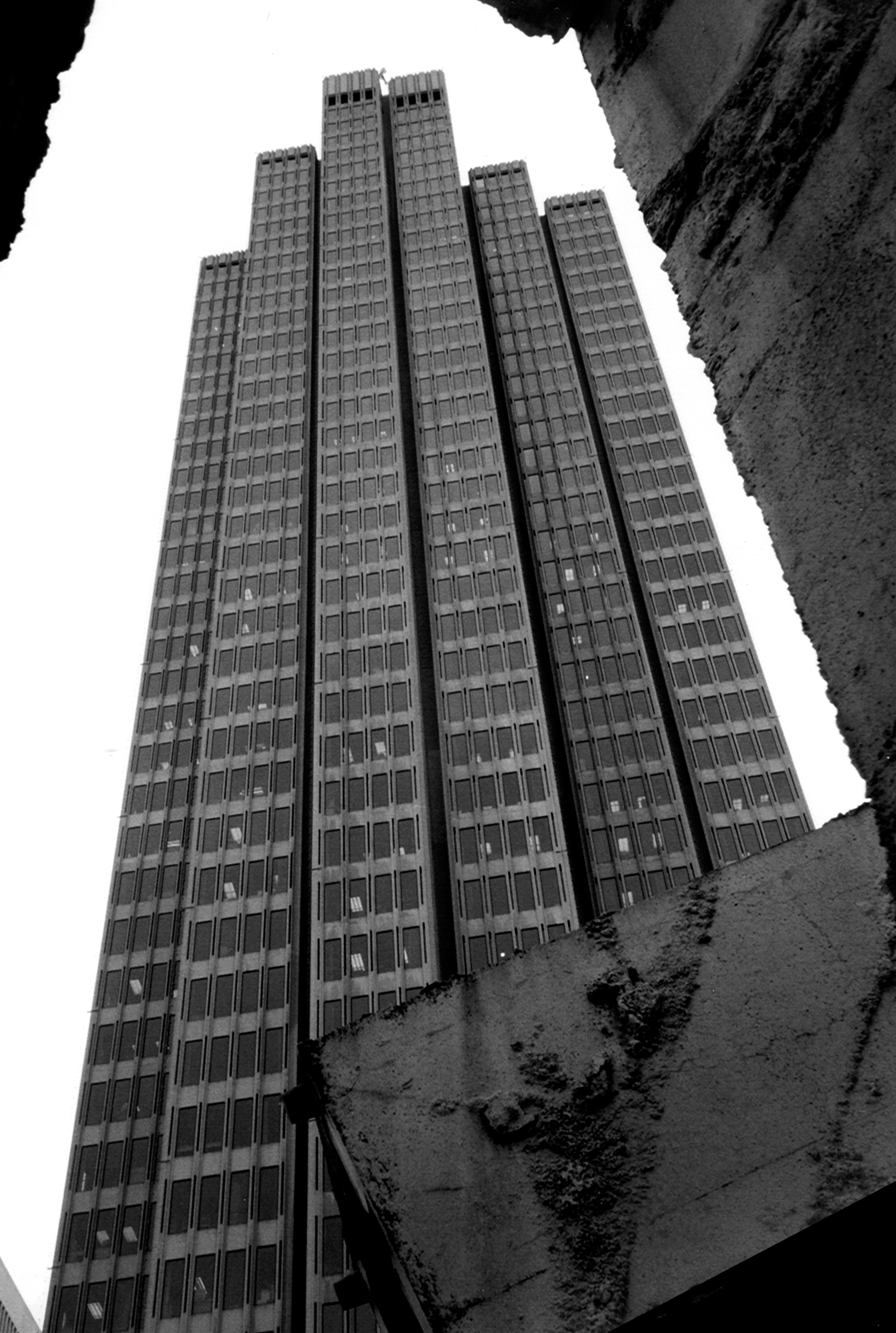 Brutalist concrete tower shot from below with repetitive grid window pattern against sky